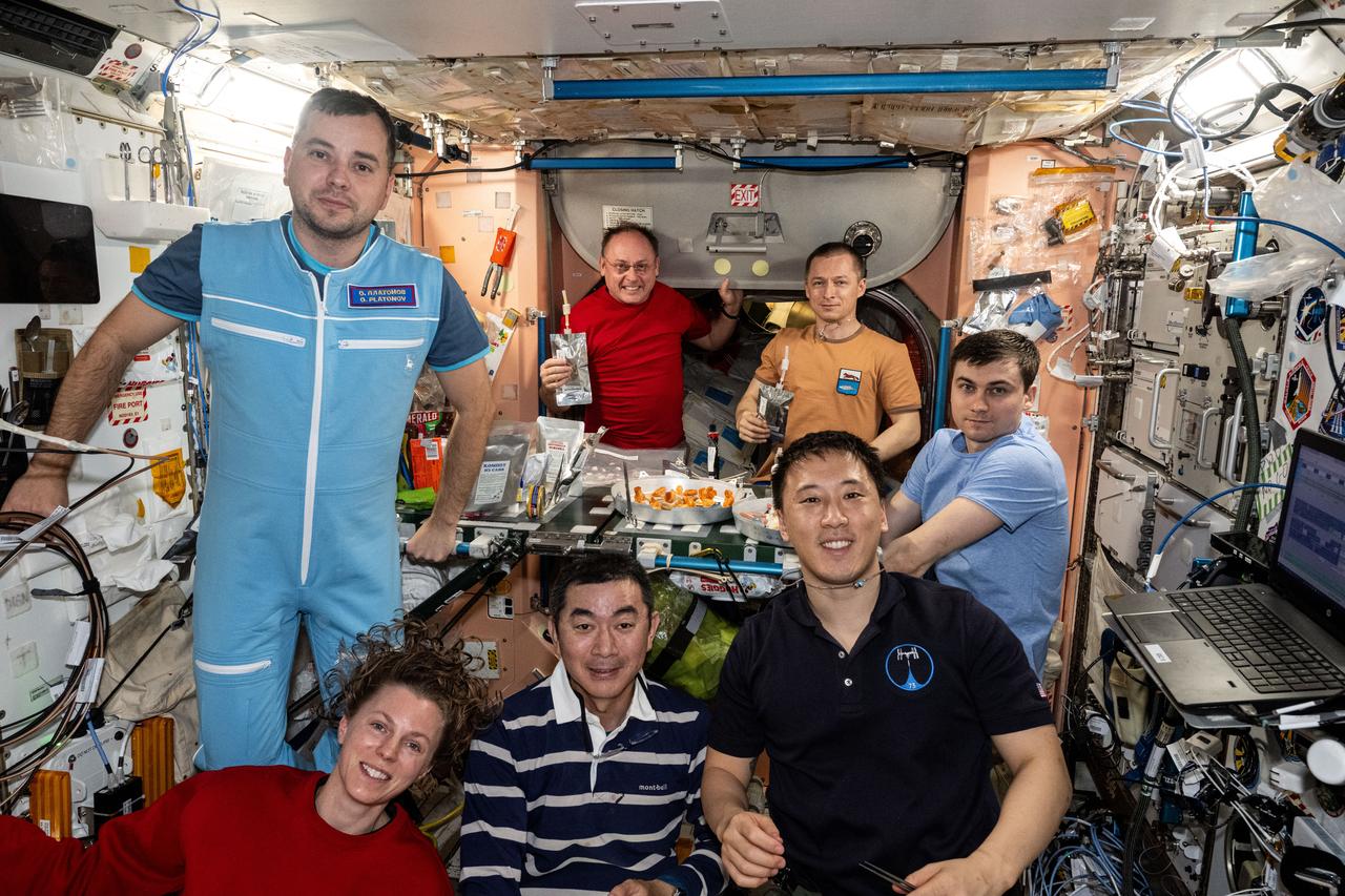 iss073e0508120 (Aug. 15, 2025) --- The seven-member Expedtion 73 crew gathers together for a dinnertime portrait inside the galley of the International Space Station's Unity module. In the front from left are, Flight Engineers Zena Cardman of NASA, Kimiya Yui of JAXA (Japan Aerospace Exploration Agency), and Jonny Kim of NASA. In the back are, Flight Engineers Oleg Platonov of Roscosmos and Mike Fincke of NASA, and station Commander Sergey Ryzhikov and Alexey Zubritsky, both from Roscosmos.