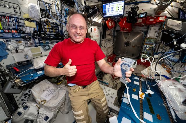 NASA image: NASA astronaut gives a “thumbs up” while holding a spacesuit camera 