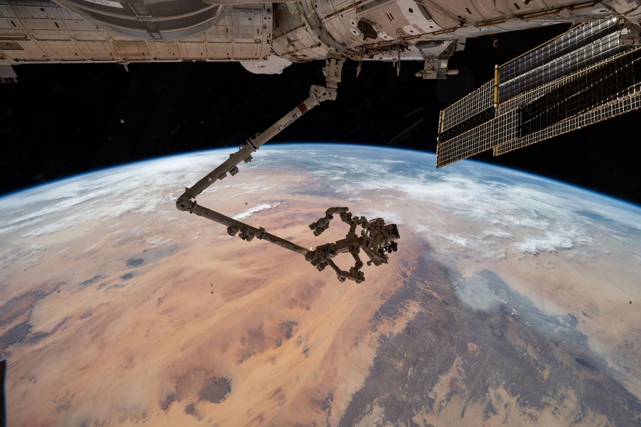 iss073e0546366 (Aug. 27, 2025) --- The International Space Station's 57.7-foot-long robotic arm, Canadarm2, with its fine-tuned robotic hand, Dextre, attached is pictured extending from the International Space Station's Harmony module. The orbital outpost was soaring 260 miles above the Saharan Desert in Libya at the time of this photograph.