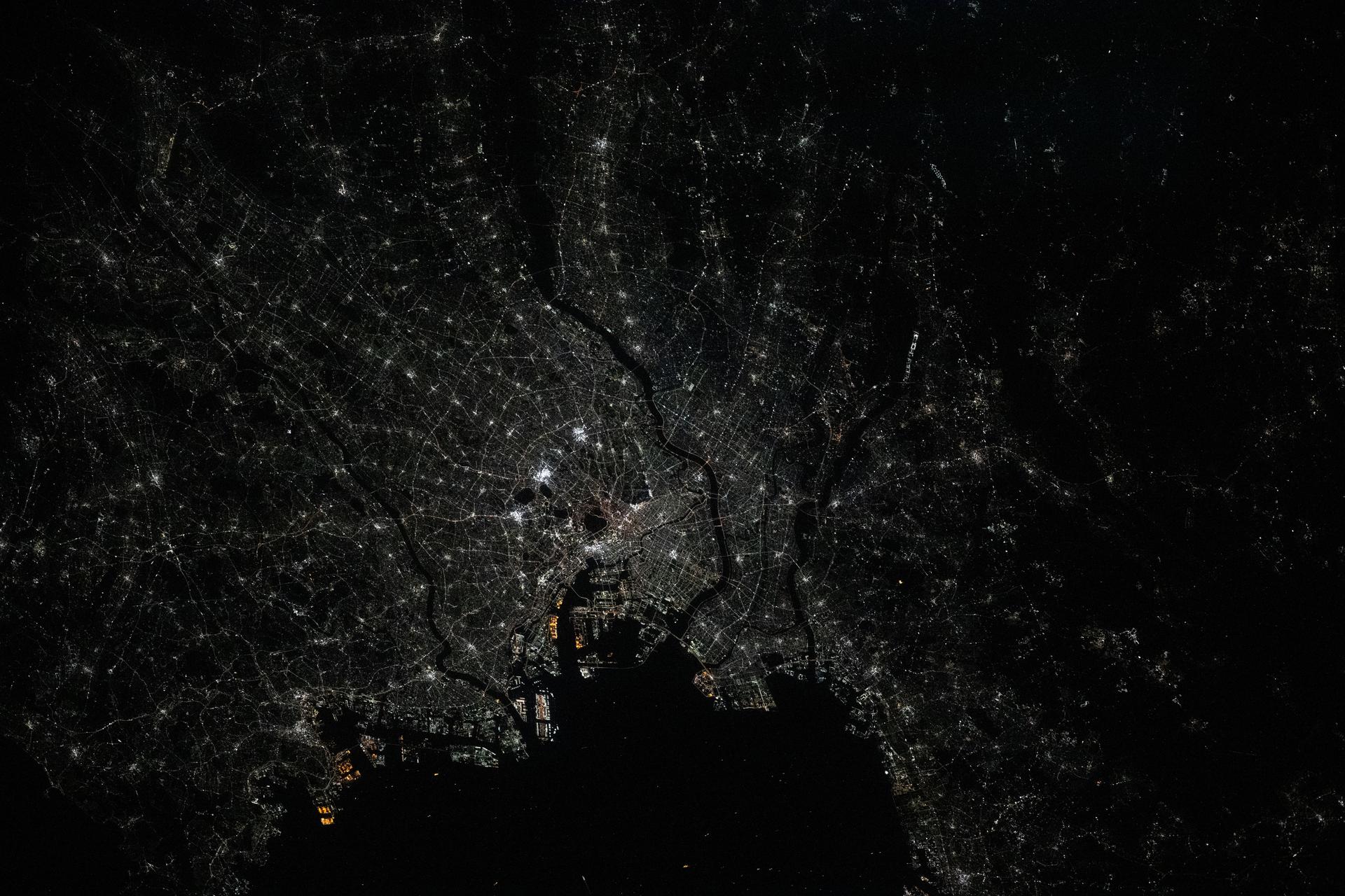 Tokyo, Japan, and its surrounding suburbs—the world’s most populous metropolitan area with about 39.1 million people—are pictured at approximately 1 a.m. local time from the International Space Station as it orbited 262 miles above. Visible landmarks include Haneda Airport on Tokyo Bay (lower center) and the Imperial Palace (the dark area at center) in the heart of downtown Tokyo.