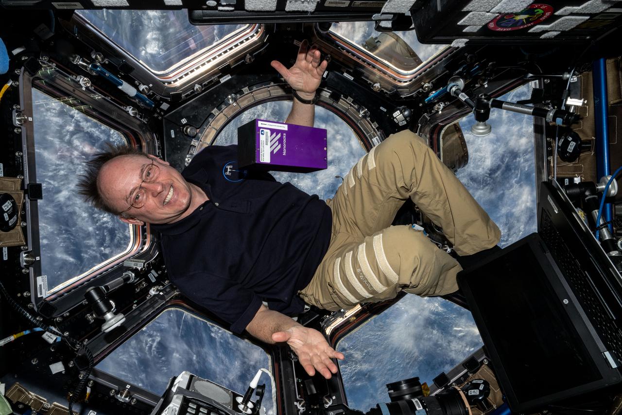 iss073e0548503 (Aug. 28, 2025) --- NASA astronaut and Expedtion 73 Flight Engineer Mike Fincke displays the Nanoracks' Nanolab Space Liintech research hardware inside the International Space Station's cupola while orbiting 262 miles above a cloudy United States. Nanolab Space LiinTech tests a platform that uses optical technology to monitor the process of producing protein crystals in microgravity. This investigation could lead to the development of technology for crystallizing proteins in microgravity to produce pharmaceuticals for use in space and Earth.