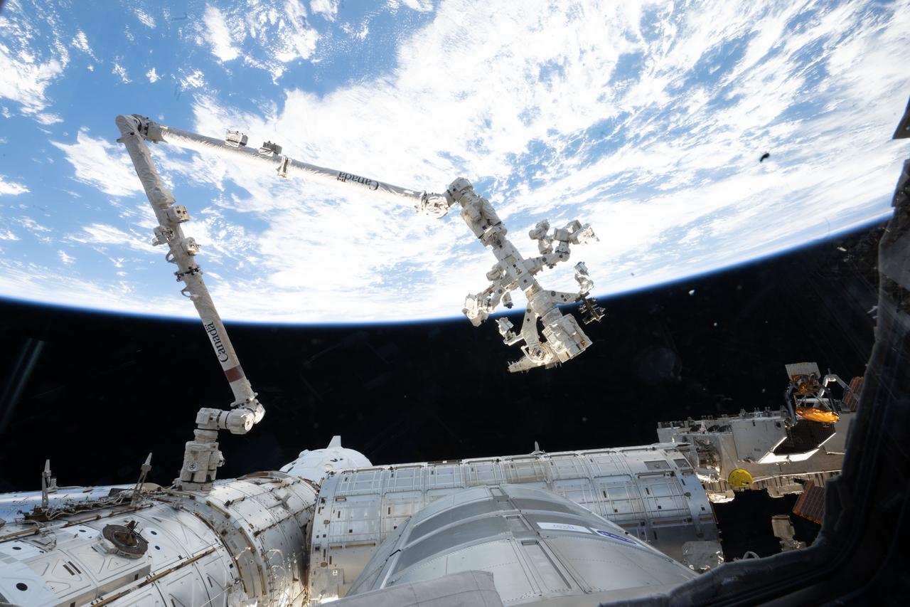 iss073e0575226 (July 23, 2025) --- The 57.7-foot-long Canadarm2 robotic arm extends from a data grapple fixture on the International Space Station’s Harmony module. Attached to its latching end effector is Dextre, the station’s fine-tuned robotic hand designed for delicate external maintenance tasks. The SpaceX Dragon crew spacecraft, partially obscured, is docked to Harmony’s forward port 259 miles above a cloudy Pacific Ocean southwest of Mexico.