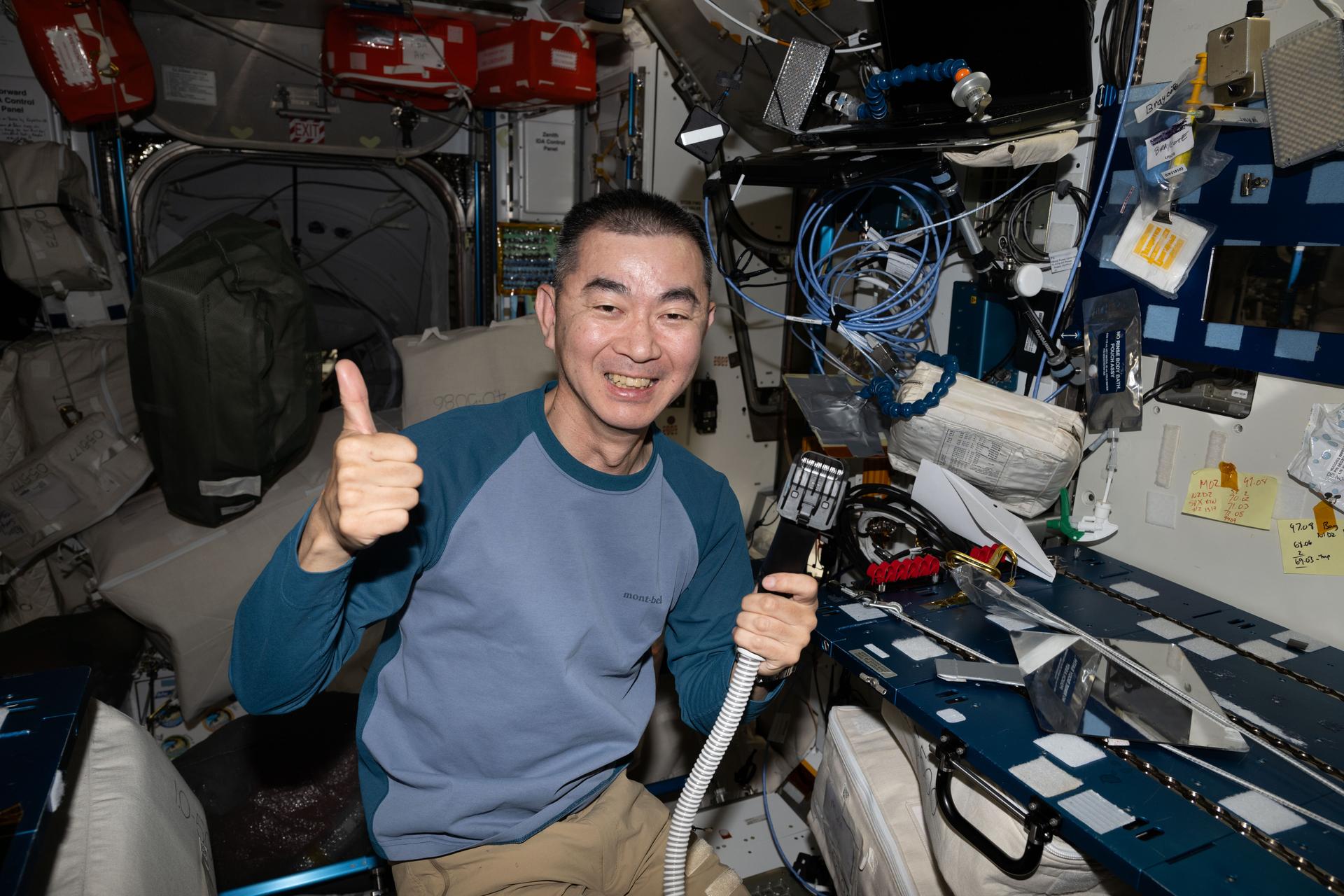 Astronaut Kimiya Yui of JAXA (Japan Aerospace Exploration Agency) smiles for a portrait after trimming his own hair aboard the International Space Station. Attached to the electric razor is a vacuum that collects the loose hair safeguarding the station's atmosphere in the microgravity environment.