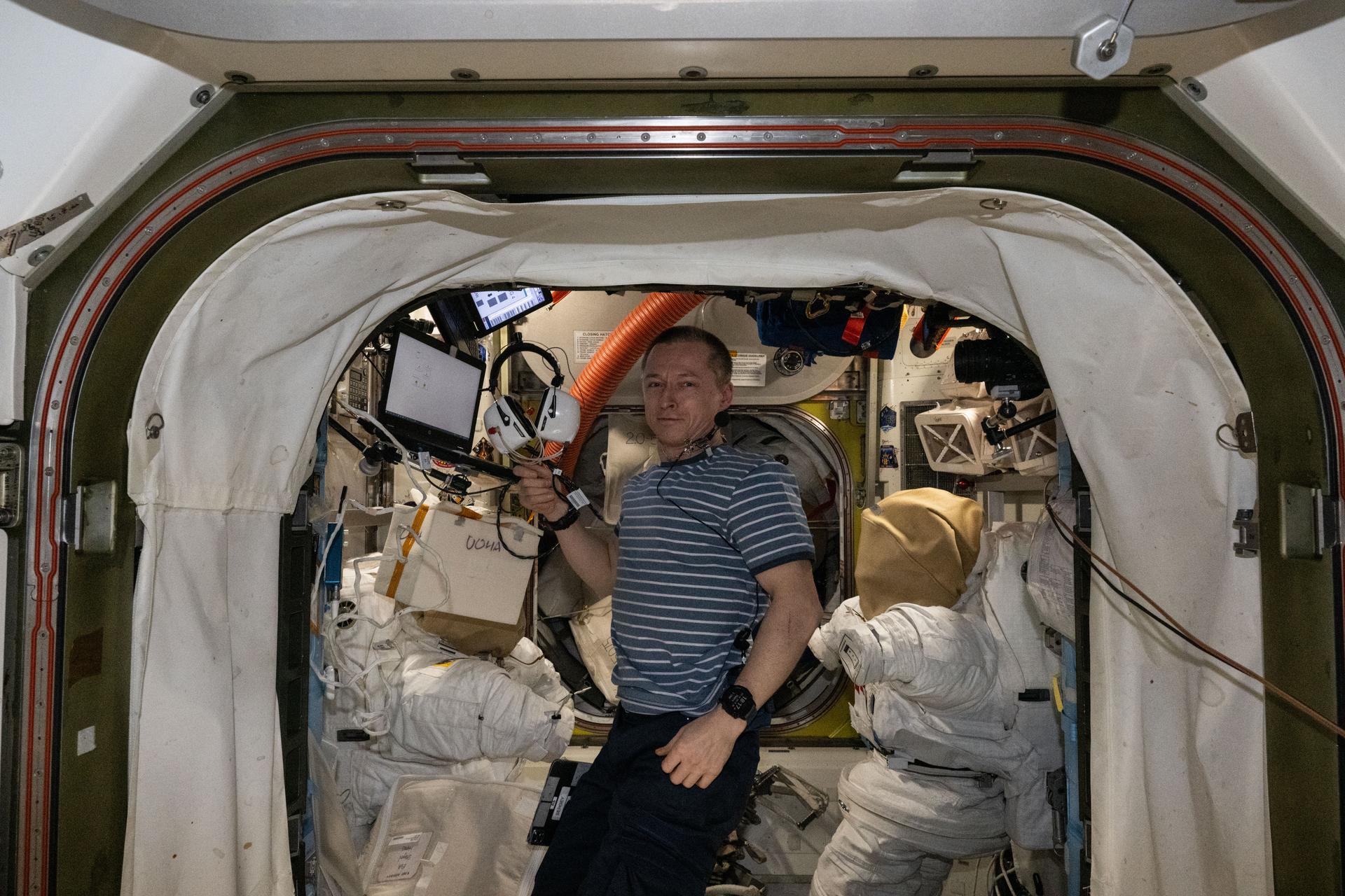 Roscosmos cosmonaut and Expedition 73 Commander Sergey Ryzhikov holds a headset inside the International Space Station's Quest airlock. Ryzhikov was conducting a hearing examination frequently conducted inside Quest due to the module's quiet environment. Quest is used primarily to service spacesuits and stage spacewalks.