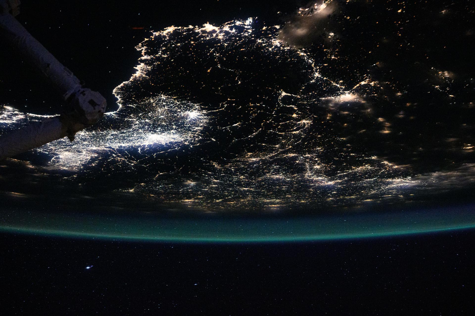 The atmospheric glow blankets southern Europe and the northwestern Mediterranean coast, outlined by city lights. At left, the Po Valley urban corridor in Italy shines with the metropolitan areas of Milan and Turin and their surrounding suburbs. This photograph was taken at approximately 1:39 a.m. local time from the International Space Station as it orbited 261 miles above Earth.