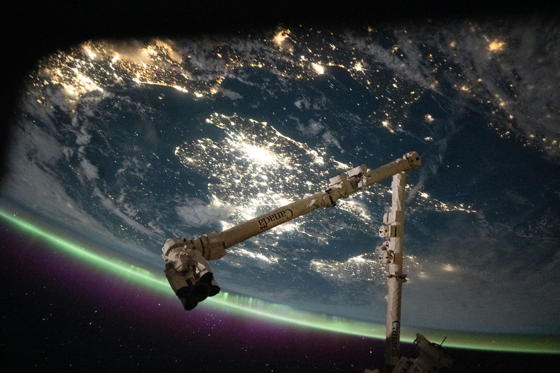 The English Channel separates the sparkling nighttime coasts of France and England highlighted by an aurora crowning Earth's atmosphere. The sprawling city lights of London are seen at center, while the coastal cities of northern Europe including Amsterdam can be seen at top left. In the foreground, is the Canadarm2 robotic arm. The International Space Station was orbiting 263 miles above France at approximately 11:38 p.m. local time when this photograph was taken.