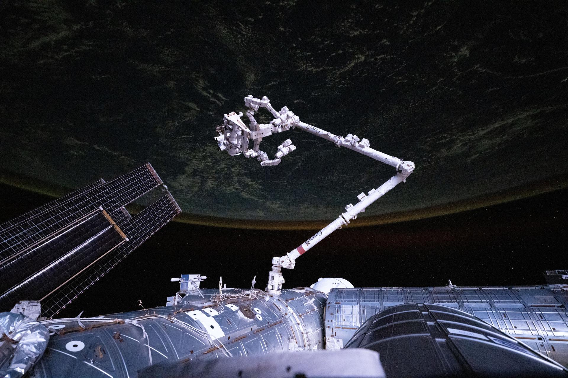 The International Space Station's U.S. segment gleams during an orbital sunset whle soaring 262 miles above the southern Indian Ocean. Dominating the foreground is the Canadarm2 robotic arm with Dexter, its fine-tuned robotic hand, extending from a data grapple fixture on the station's Harmony module.