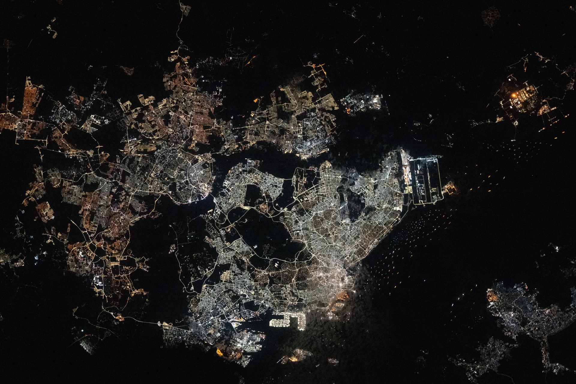 The Southeast Asian city-state of Singapore (center), separated from Johor Bahru, Malaysia (left), by the Johor Strait, is pictured at approximately 12:34 a.m. from the International Space Station as it orbited 260 miles above. Singapore Changi Airport (right center) sits along the Straits of Singapore and features the world’s tallest indoor waterfall and a forest with over 2,000 trees and 100,000 shrubs. The bright rectangular area at bottom center is Pasir Panjang Terminal, designed to accommodate some of the world’s largest container vessels.