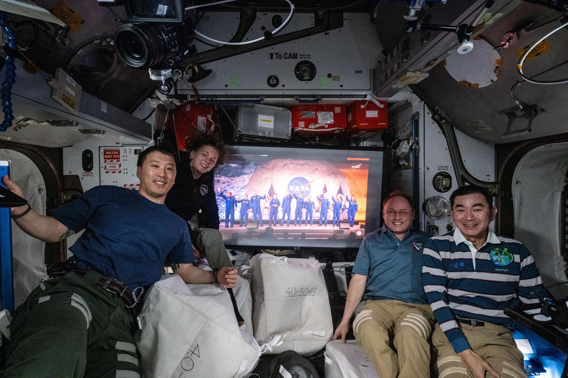 Four Expedition 73 flight engineers gather together inside the International Space Station's Harmony module and watch NASA's announcement of its 2025 Astronaut Candidate Class from the Johnson Space Center in Houston, Texas. From left, are NASA astronauts Jonny Kim, Zena Cardman, and Mike Fincke, and JAXA (Japan Aerospace Exploration Agency) astronaut Kimiya Yui.