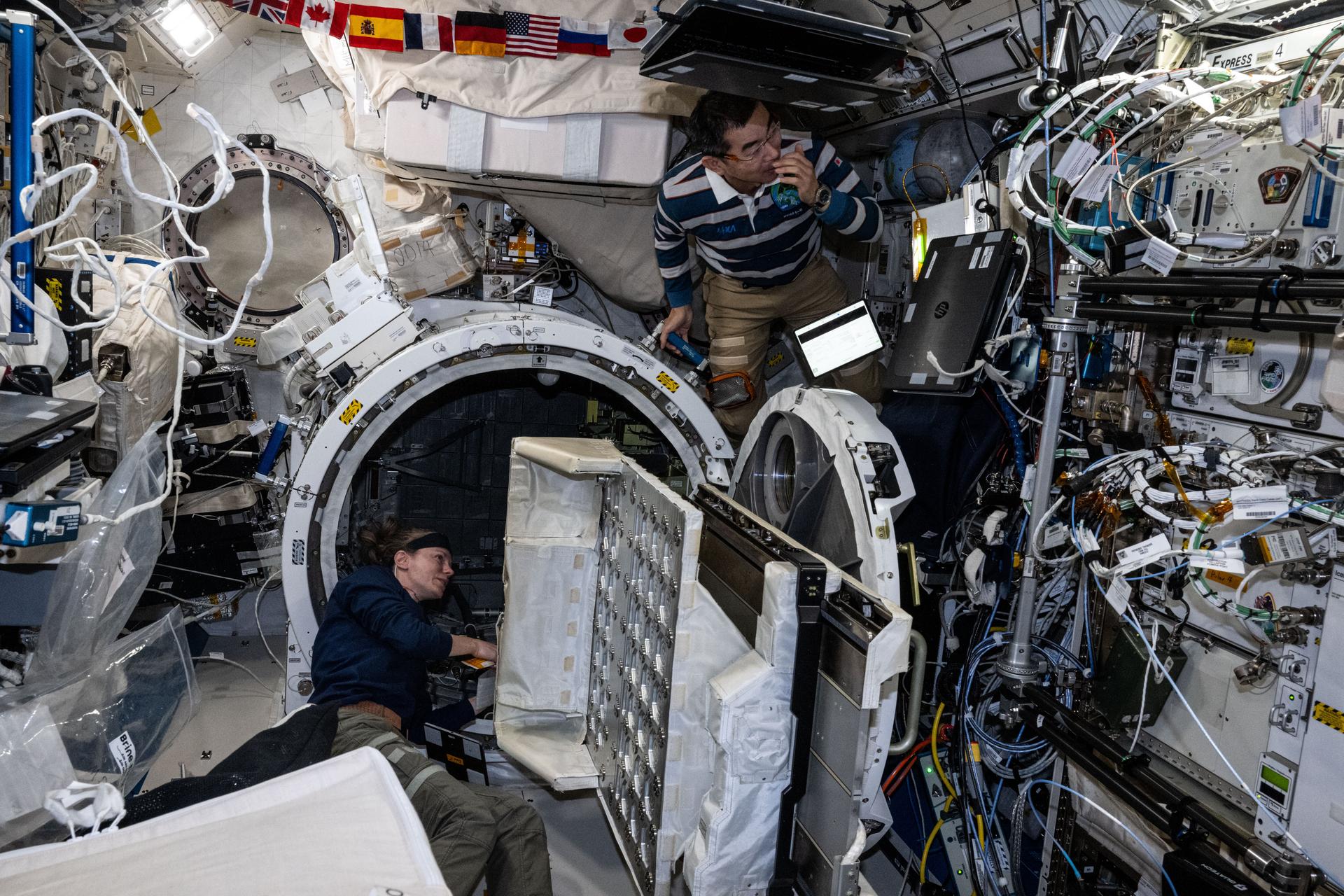 iss073e0768346 (Sept. 25, 2025) --- Expedition 73 Flight Engineers Zena Cardman of NASA and Kimiya Yui of JAXA (Japan Aerospace Exploration Agency) partner together inside the International Space Station's Kibo laboratory module removing a small satellite orbital deployer from inside Kibo's airlock