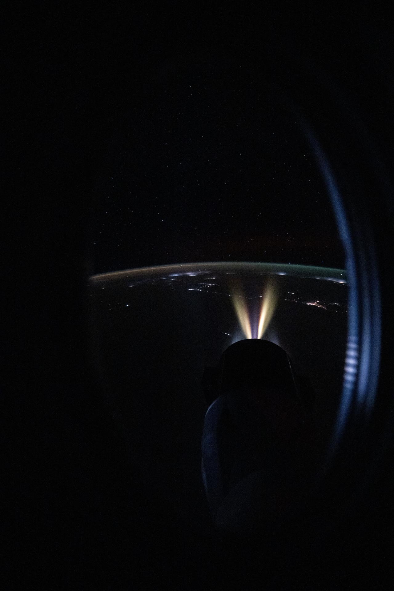 This nighttime image was captured from a window aboard the SpaceX Dragon crew spacecraft, docked to the space-facing port of the International Space Station’s Harmony module, while orbiting 259 miles above the Indian Ocean. In the foreground, the Draco thrusters of the SpaceX Dragon cargo spacecraft, docked to Harmony’s forward port, are seen firing during a demonstration of its ability to reboost the station’s orbit. In the background, an atmospheric glow blankets Earth's horizon with the city lights on Africa's east coast dotting the dark landscape.