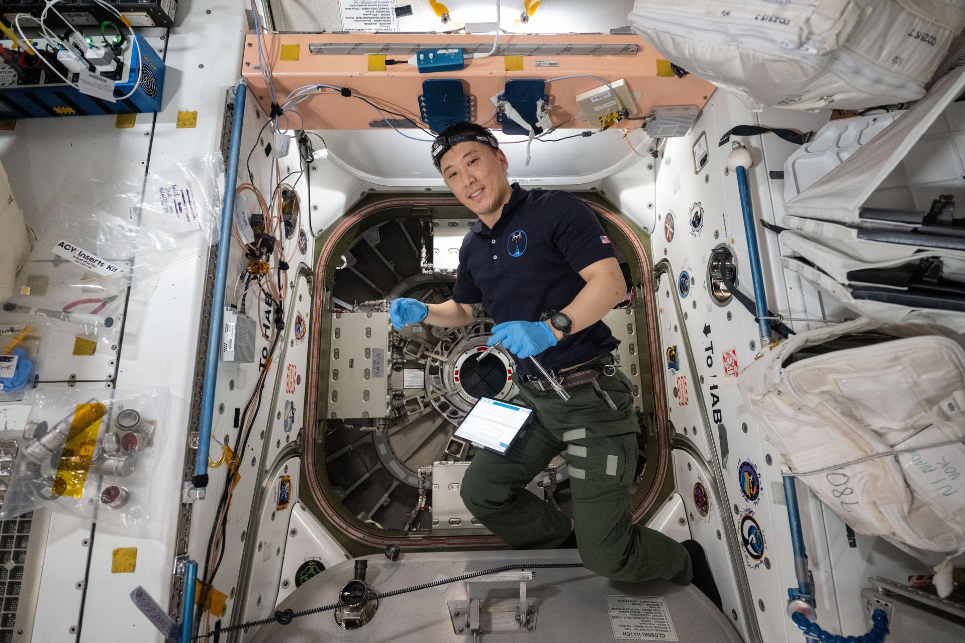iss073e0814521 (Sept. 18, 2025) --- NASA astronaut and Expedition 73 Flight Engineer Jonny Kim is pictured inside the vestibule between the International Space Station's Unity module and the Cygnus XL cargo spacecraft from Northrop Grumman. Kim was preparing to open Cygnus' hatch to begin unloading about 11,000 pounds of new science and supplies for the Expedition 73 crew.