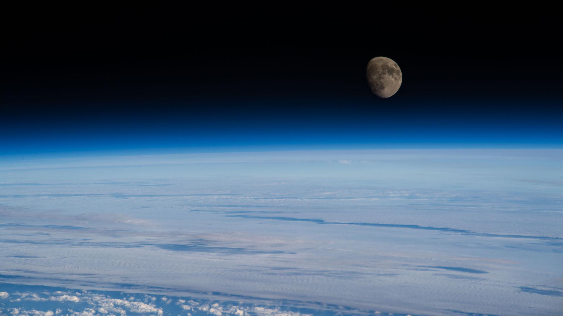 The waxing gibbous Moon rises above Earth’s blue atmosphere in this photograph taken from the International Space Station as it orbited 263 miles above a cloudy Atlantic Ocean off the coast of Quebec, Canada.