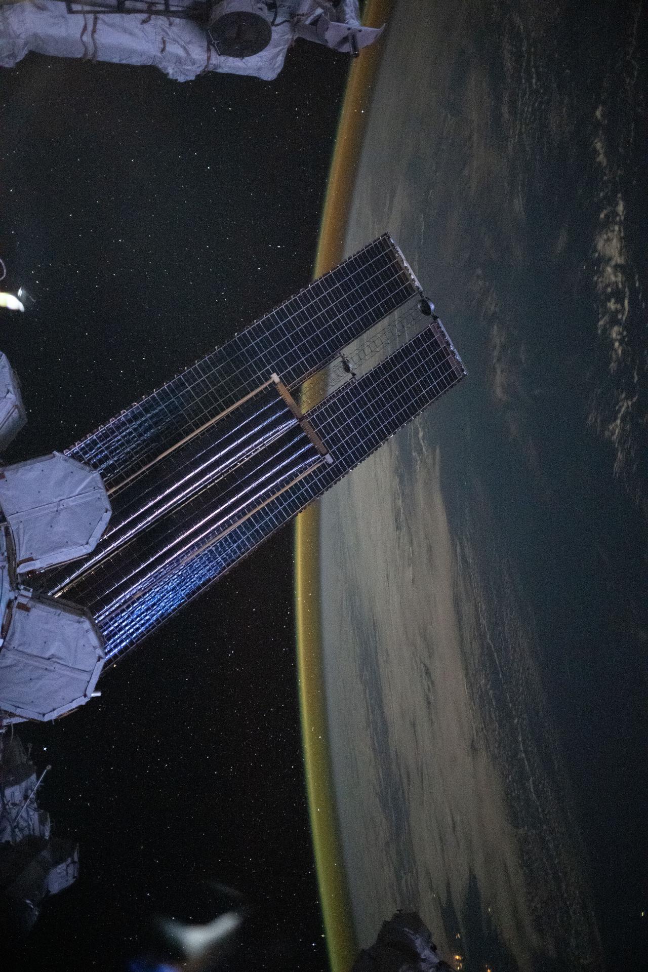 A dim, yellow-green airglow crowns Earth’s horizon between northwestern Australia and Indonesia’s Lesser Sunda Islands. In the foreground, a set of the orbital outpost’s main solar arrays, partially overlapped by a smaller set of roll-out solar arrays, stretches across the frame. The International Space Station was soaring 262 miles above the tranquil Indian Ocean at approximately 4:07 a.m. local time when this photograph was taken.