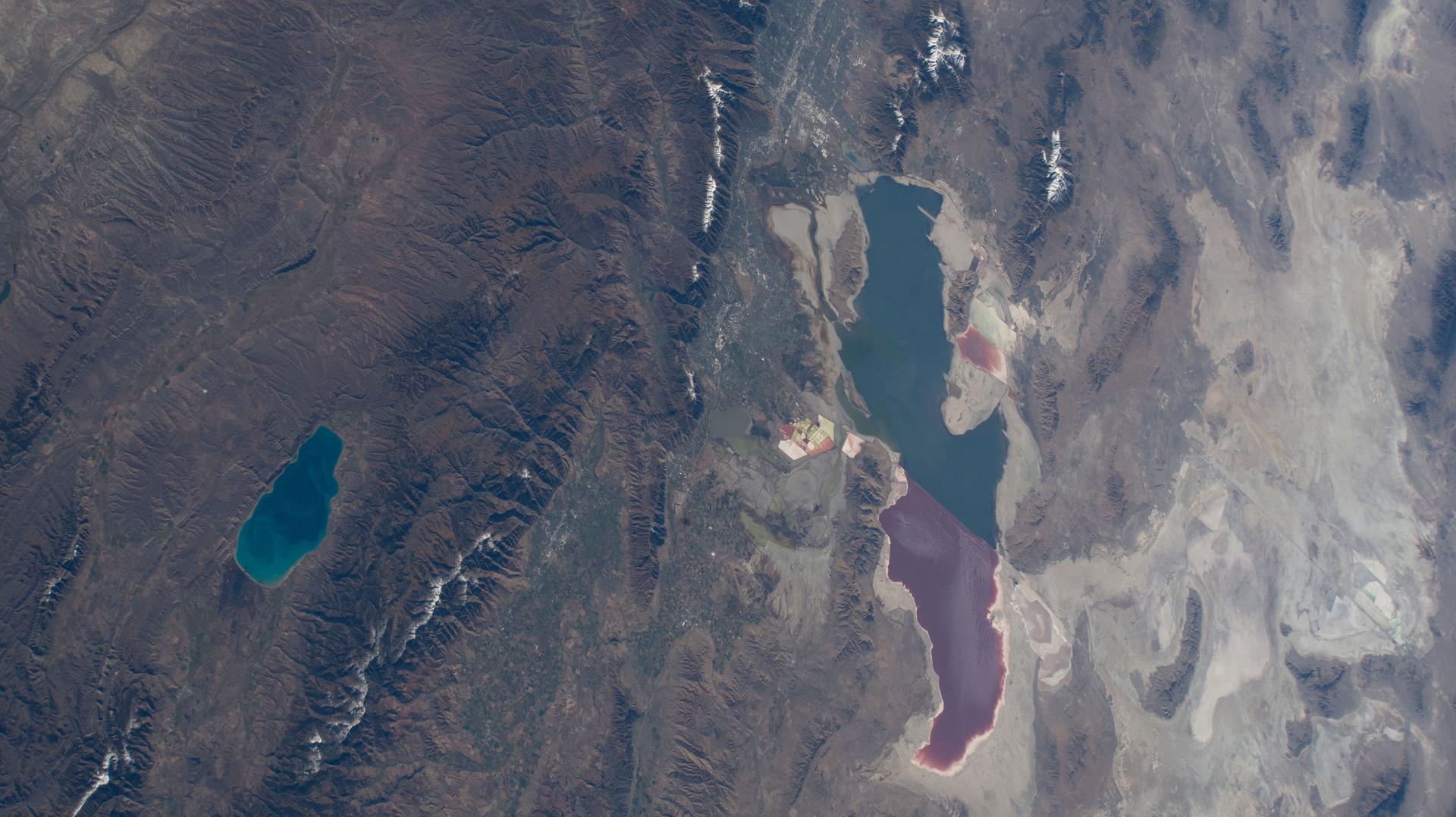 Bear Lake (left) is a freshwater lake spanning Idaho and Utah, and is smaller and much deeper than Utah's Great Salt Lake—averaging 208 feet compared to just 14 feet. The distinct color differences in the Great Salt Lake are caused by a railroad causeway: the red portion has much higher salinity than the blue, less saline section.