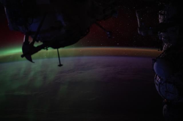 NASA image: A wispy green aurora australis fades into a dim orange-yellow airglow above Earth’s horizon