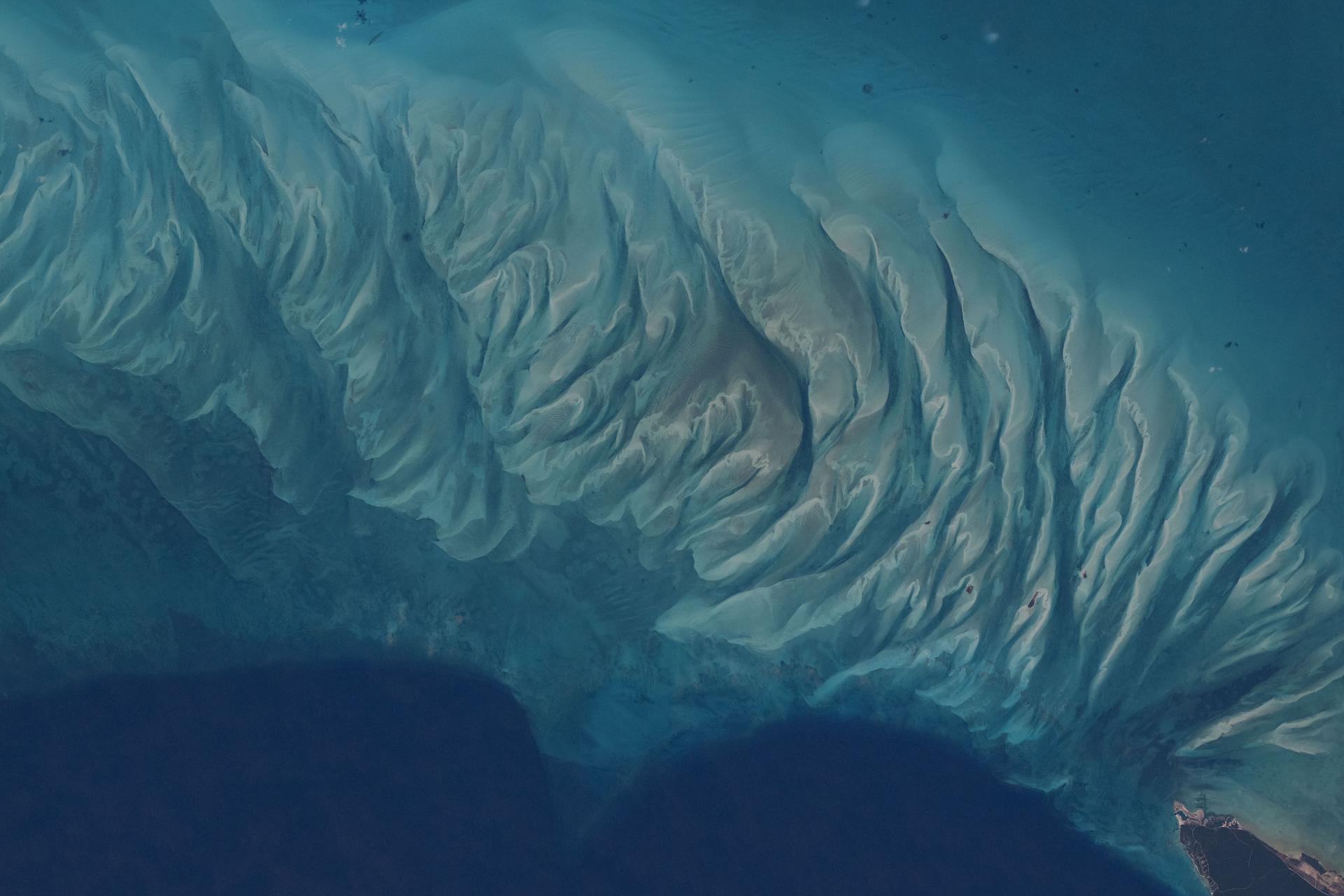 iss073e0880792 (Oct. 15, 2025) --- The clear blue waters off the coast of the Bahamian island of Eleuthera—part of which is visible at lower right—reveal sandbars and submerged dunes rippling across the seafloor shaped by currents and waves in the western Atlantic. The International Space Station was orbiting 260 miles above Earth when this photograph was taken.