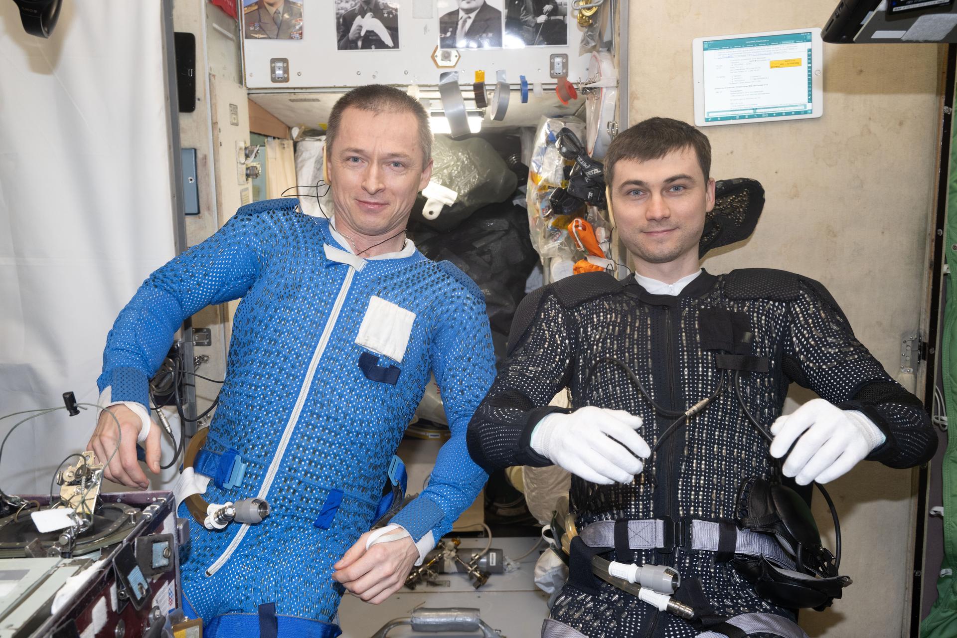 Roscosmos cosmonauts (from left) Sergey Ryzhikov and Alexey Zubritsky are pictured inside the International Space Station's Zvezda service module dressing up and preparing for a spacewalk. The duo would install a semiconductor materials experiment, remove a high-resolution camera monoblock, clean a window on the Zvezda service module, and remove a materials exposure experiment container during the six-hour and nine-minute excursion.