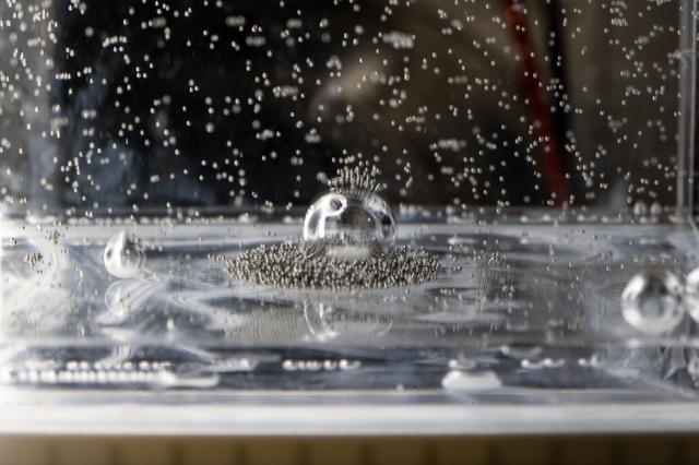 NASA image: Tiny ball bearings surround a larger central bearing during the Fluid Particles experiment