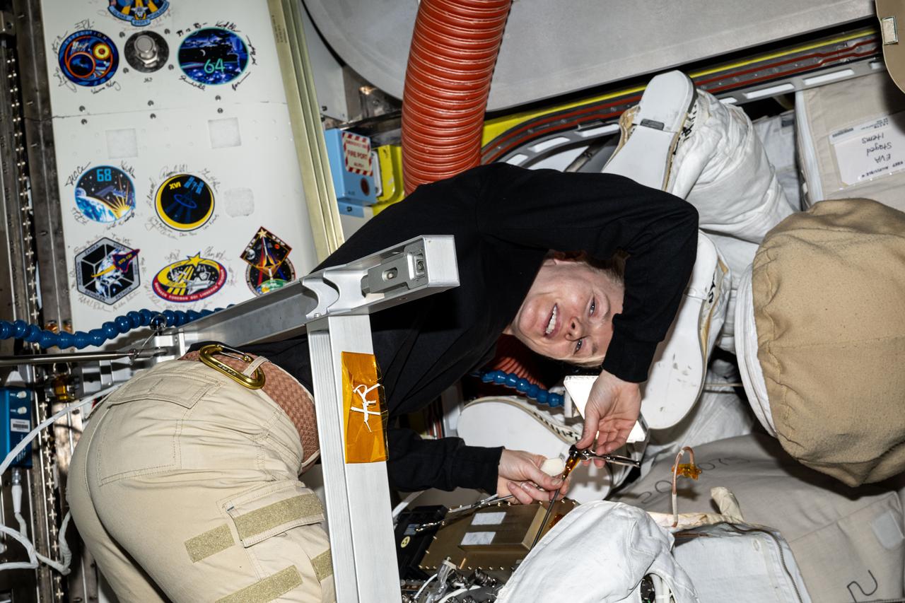 iss073e0917417 (Oct. 21, 2025) --- NASA astronaut and Expedition 73 Flight Engineer Zena Cardman performs communications maintenance swapping radios and checking their peformance on a pair of spacesuits inside the International Space Station's Quest airlock.