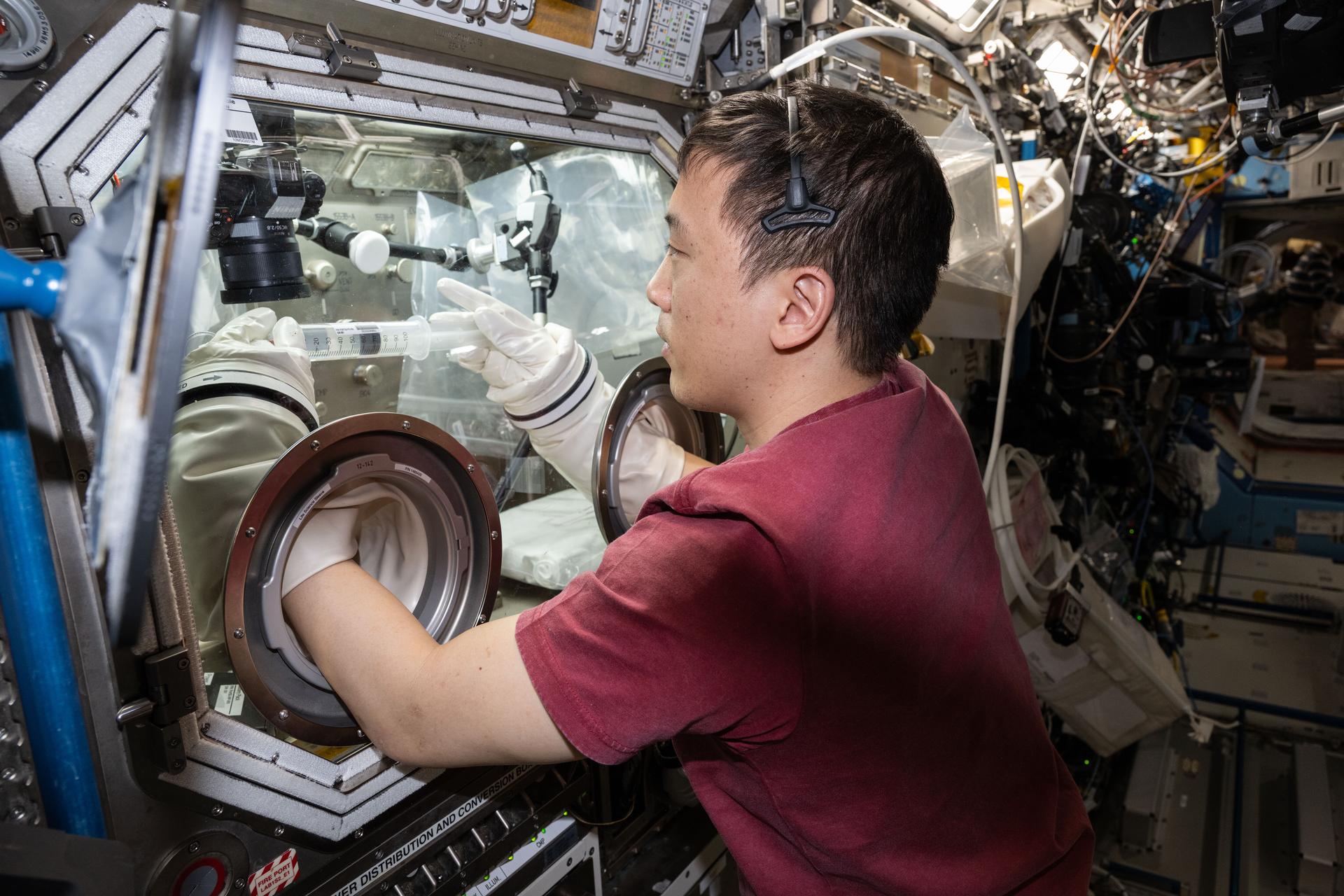 NASA astronaut and Expedition 73 Flight Engineer Jonny Kim conducts research operations for the Fluid Particles investigation inside the Microgravity Science Glovebox aboard the International Space Station's Destiny laboratory module. The fluid physics experiment may help researchers understand how particles in a liquid interface come together to form larger structures or clusters in microgravity advancing fire suppression, lunar dust control, and plant growth in space. Earth benefits may include insights into pollen behavior, algae blooms, plastic pollution, and sea salt transfer during storms.