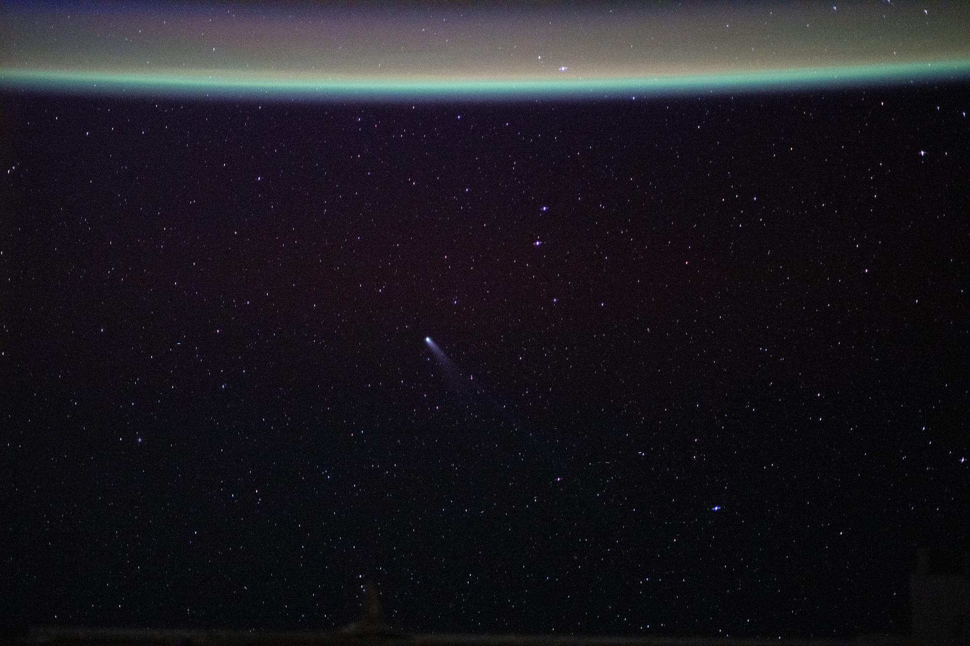 Comet Lemmon (C/2025 A6) is visible near the center of the frame, approximately 55.4 million miles (89.2 million kilometers) from Earth, in this photograph taken from the International Space Station as it orbited 262 miles above northwestern China. At the top, a blue-green airglow blankets Earth’s horizon.