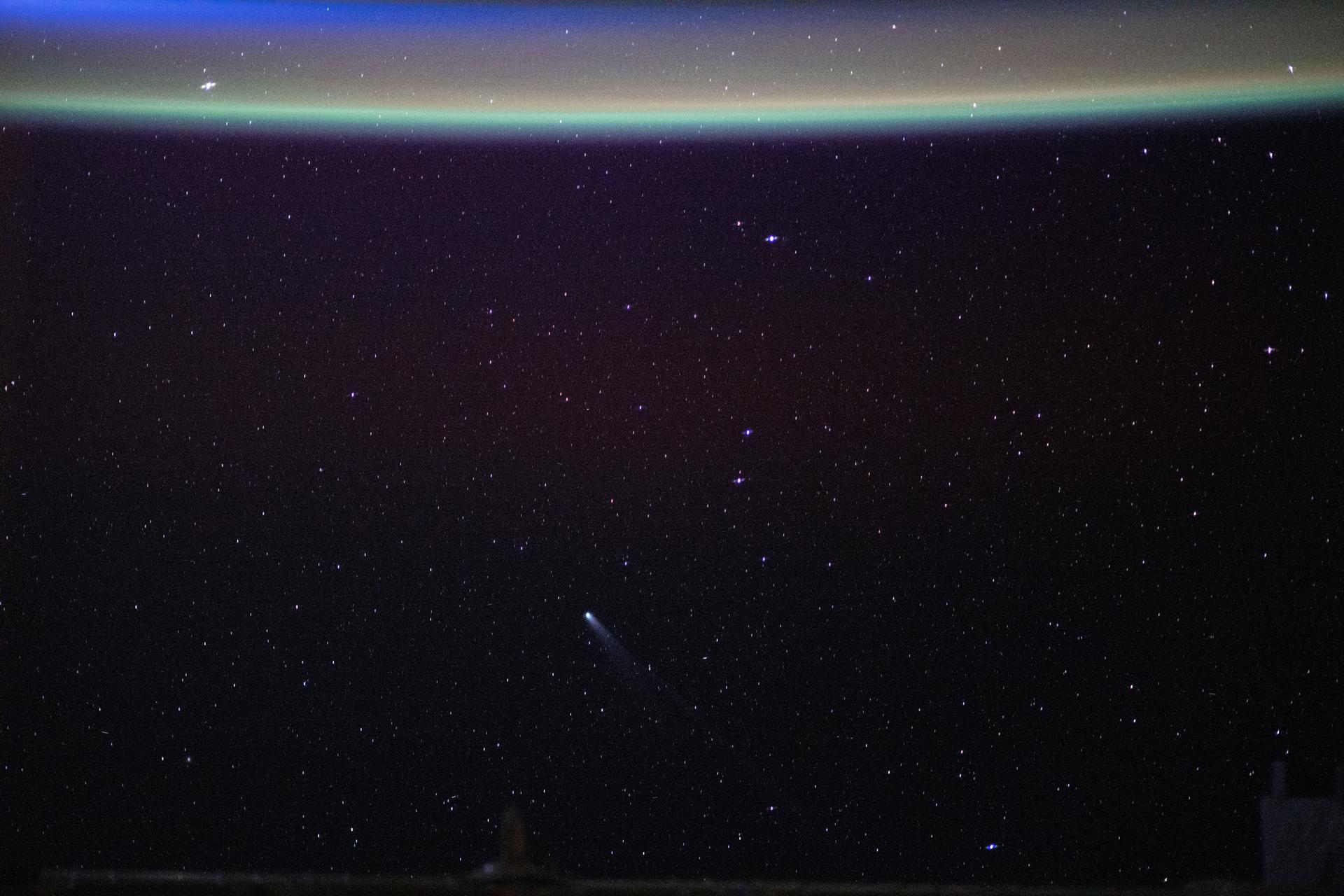 Comet Lemmon (C/2025 A6) is visible near the lower center of the frame, approximately 55.4 million miles (89.2 million kilometers) from Earth, in this photograph taken from the International Space Station as it orbited 262 miles above northwestern China. At the top, a green airglow blankets Earth’s horizon just moments before an orbital sunrise begins to illuminate the atmosphere.