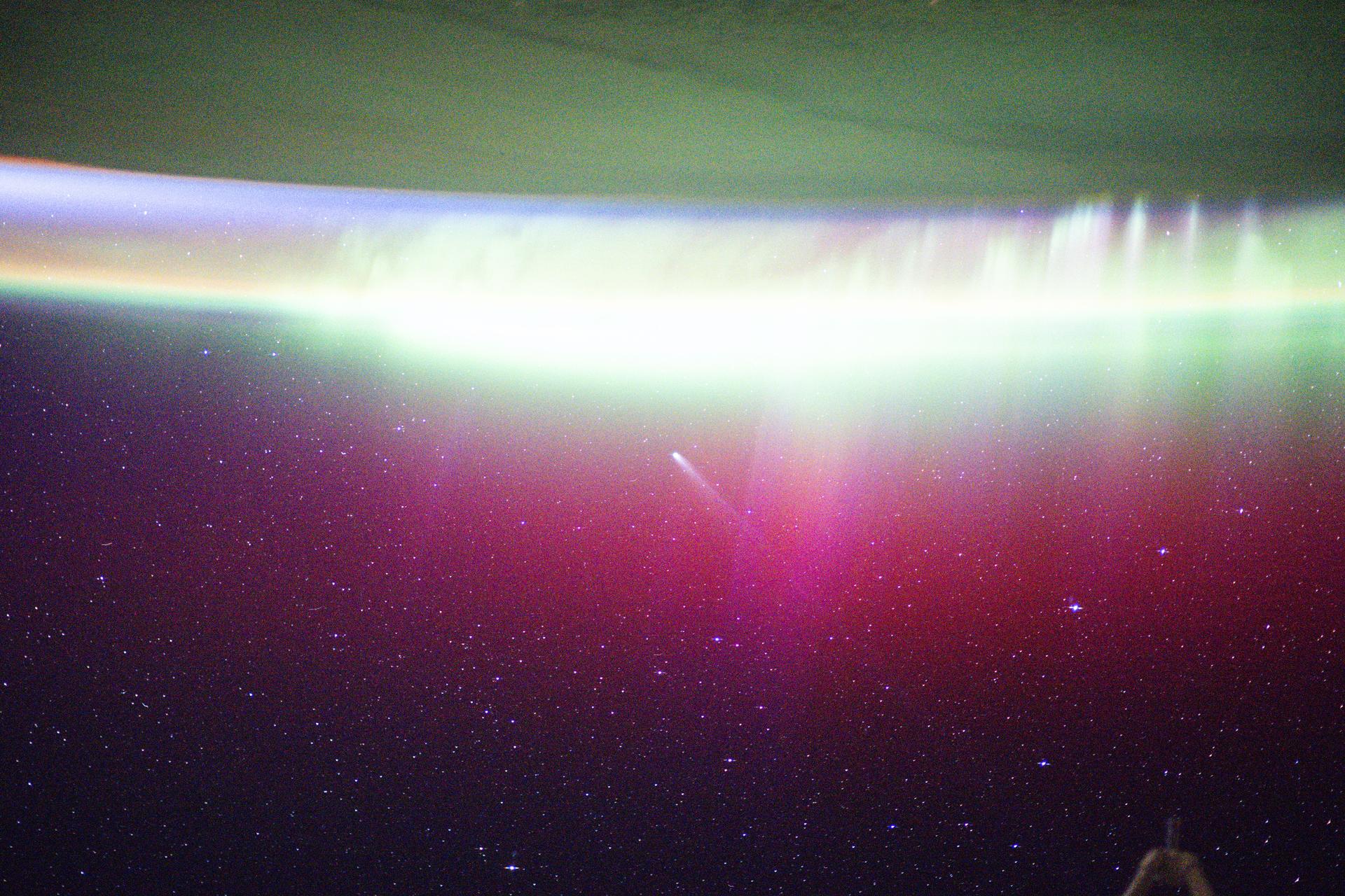 A bright, neon-like aurora radiates above Earth, seemingly absorbing Comet Lemmon (C/2025 A6) as it soars past the planet at a distance of about 57.2 million miles (92.1 million kilometers). The International Space Station was orbiting 263 miles above Fargo, North Dakota, at the time of this photograph.