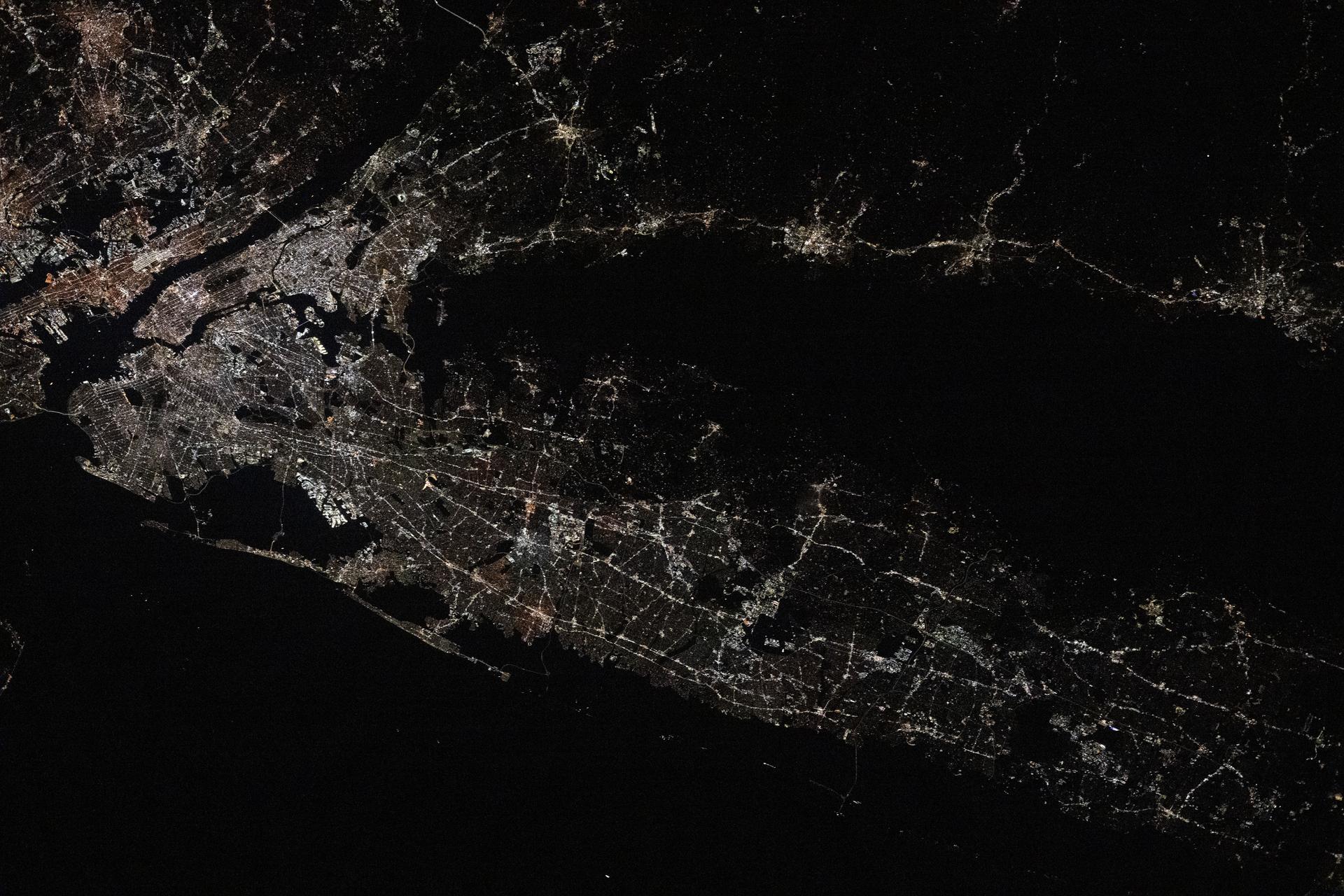 Long Island, New York—the most populous island in the United States—stretches 118 miles from west to east, extending from Brooklyn to Montauk Point. It lies between Long Island Sound to the north and the New York/New Jersey Bight to the south. Toward the upper left, New York City's island borough of Manhattan is visible, with the Hudson River and East River flowing on either side. The city's bright lights contrast with the elongated, darkened area of Central Park. This image was captured at approximately 2:24 a.m. local time from the International Space Station as it orbited 263 miles above the Empire State.