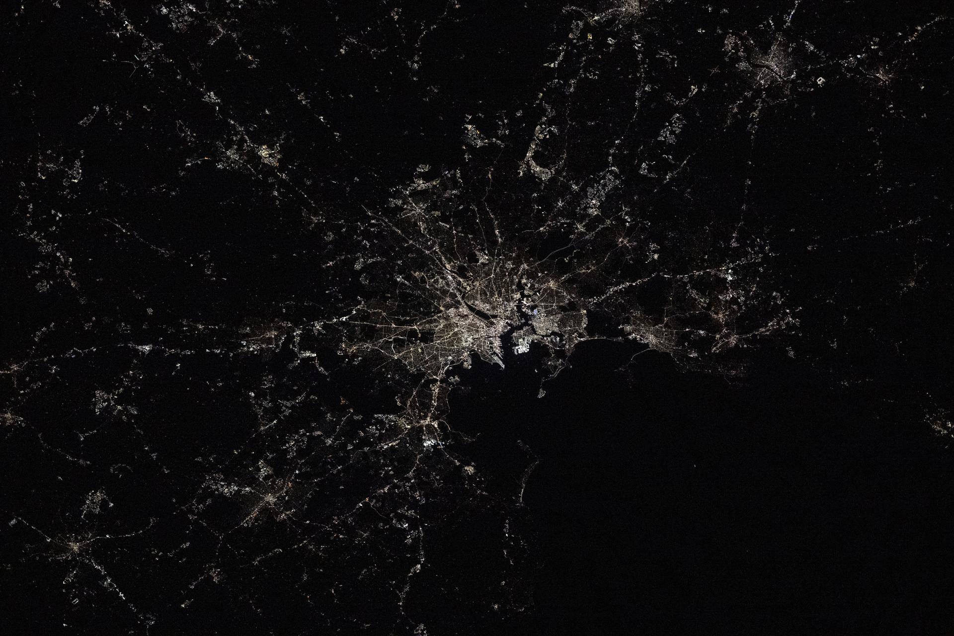 Boston, Massachusetts—home to America's first public park, public school, and subway system—is pictured at approximately 2:24 a.m. local time from the International Space Station as it orbited 263 miles above the northeastern United States. Located on Boston Harbor, Boston Logan International Airport (center) opened in 1923 and handled 43.5 million passengers and 568 million pounds of cargo in 2024.