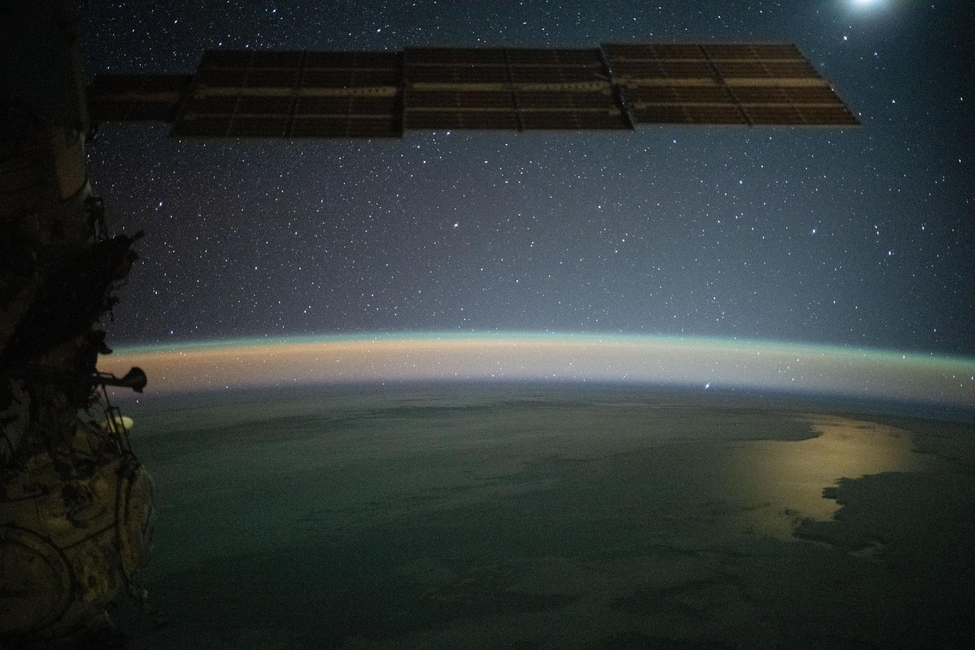 iss073e0982346 (Oct. 25, 2025) --- This serene image of the Moon (upper right) glinting off the Southern Pacific Ocean—beneath a yellow-green airglow and a starry night sky—was taken at approximately 8:59 p.m. local time from the International Space Station as it orbited 263 miles above Earth, southwest of French Polynesia, an overseas collectivity of France comprising more than 100 islands.