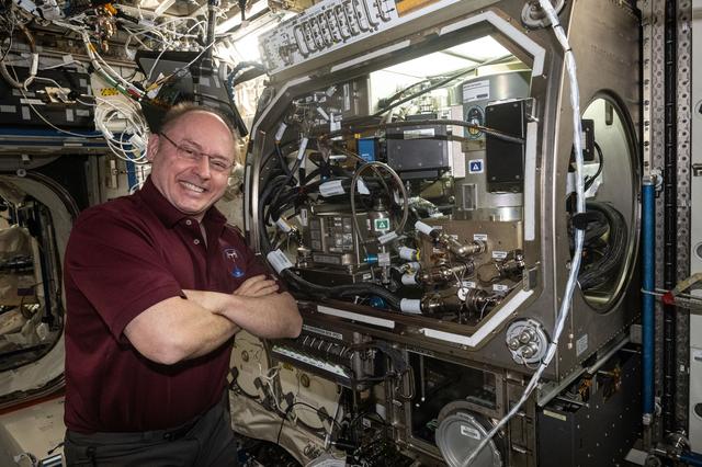 NASA image: NASA astronaut Mike Fincke poses for a portrait next to the Microgravity Science Glovebox