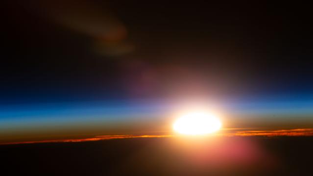 NASA image: An orbital sunrise illuminates Earth's atmosphere and cloud tops