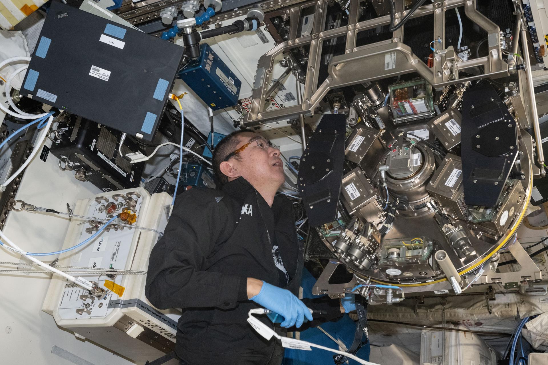 iss073e1043652 (Oct. 29, 2025) --- JAXA (Japan Aerospace Exploration Agency) astronaut and Expedition 73 Flight Engineer Kimiya Yui inspects and cleans hardware inside the Life Support Module aboard the International Space Station's Columbus laboratory module.