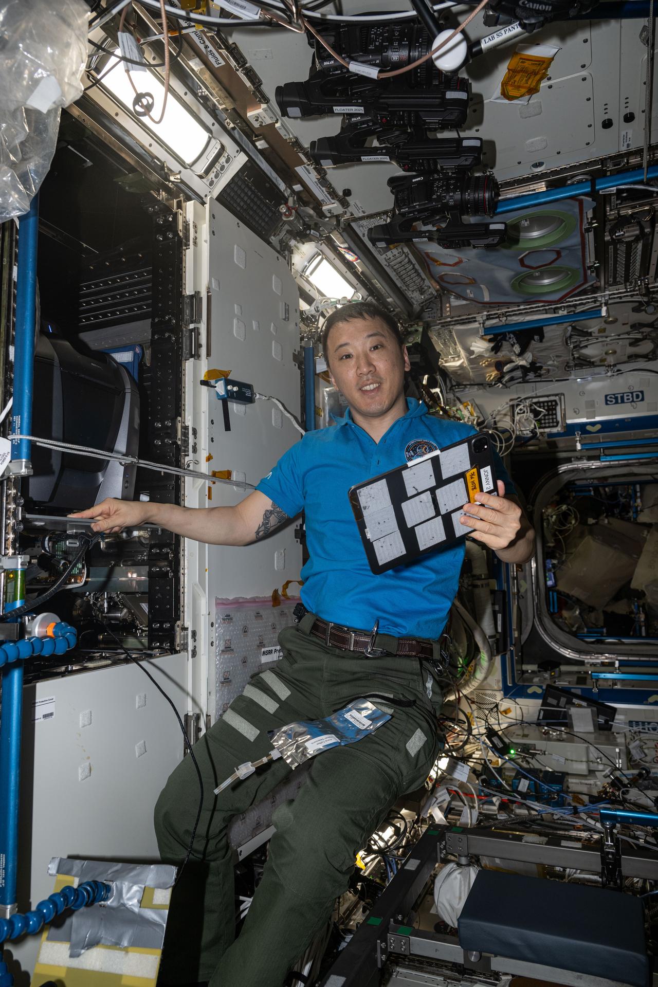NASA astronaut and Expedition 73 Flight Engineer Jonny Kim poses for a portrait while servicing the KERMIT (Keyence Research Microscope Testbed) fluorescence microscope inside the Materials Science Research Rack aboard the International Space Station’s Destiny laboratory module. KERMIT is a commercial off-the-shelf microscope that provides researchers with essential imaging capabilities for biological, physical, and materials science research in microgravity.