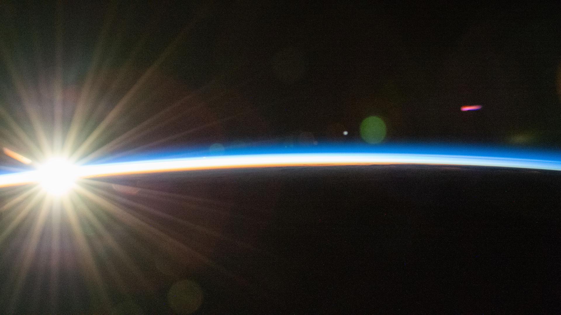 An orbital sunrise bursts above Earth's horizon and begins to illuminate the atmosphere in this photograph taken at approximately 4:11 a.m. local time from the International Space Station as it orbited 262 miles above the Pacific Ocean.
