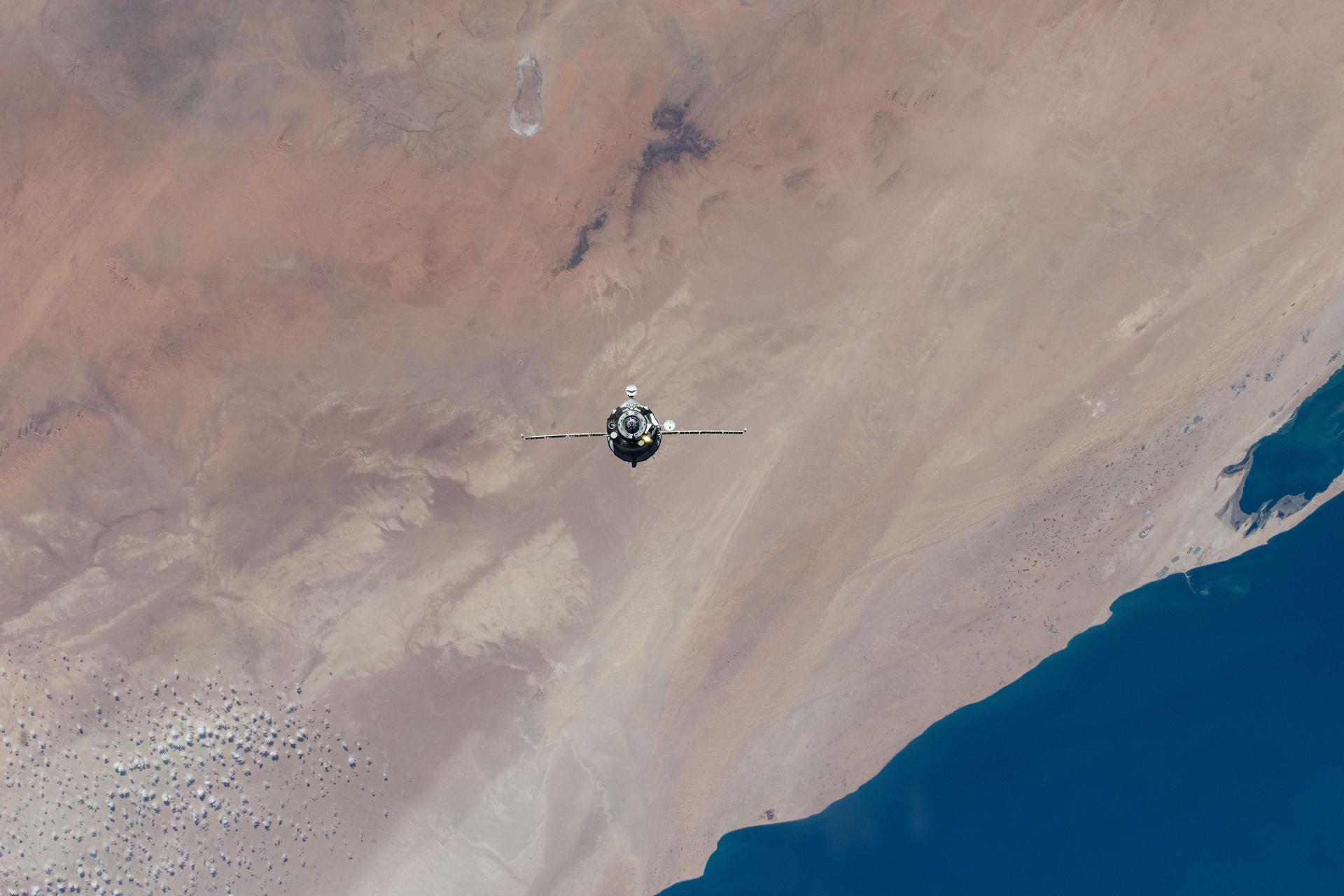 iss073e1196724 (Nov. 27, 2025) --- The Soyuz MS-28 crew spacecraft carrying NASA astronaut Chris Williams and Roscosmos cosmonauts Sergey Kud-Sverchkov and Sergei Mikaev approaches the International Space Station. Both spacecraft were orbiting 262 miles above the hot desert landscape of Western Sahara at the time of this photograph.
