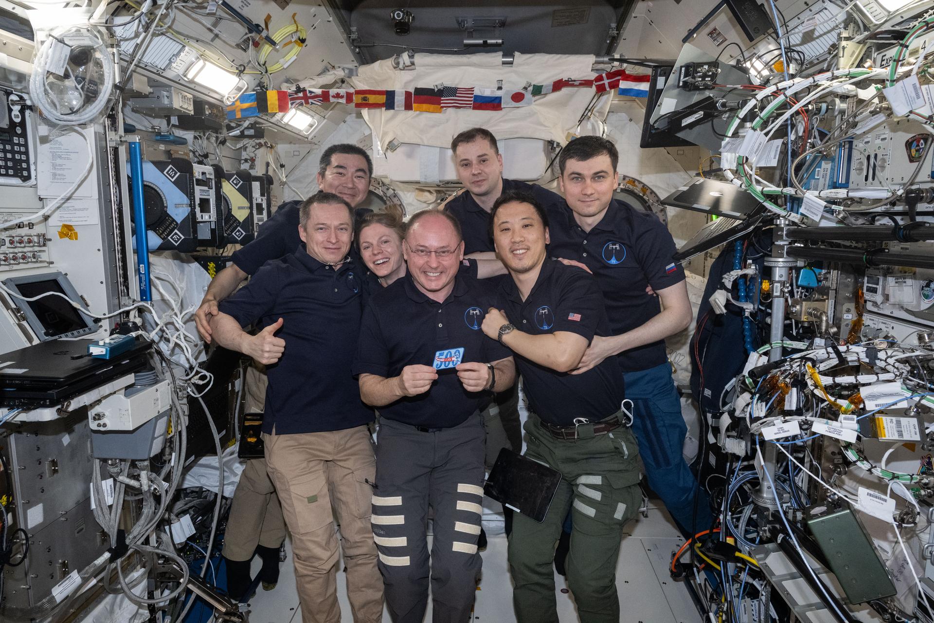 The seven-member Expedition 73 crew gathers together for a portrait inside the International Space Station's Kibo laboratory module celebrating NASA astronaut Mike Fincke's (center) 500 cumulative days in space over four missions since 2004. In the front from left are, Roscosmos cosmonaut Sergey Ryzhikov, NASA astronaut Zena Cardman, Mike Fincke, and NASA astronaut Jonny Kim. In the back are, JAXA (Japan Aerospace Exploration Agency) astronaut Kimiya Yui and Roscosmos cosmonauts Oleg Platonov and Alexey Zubritsky.