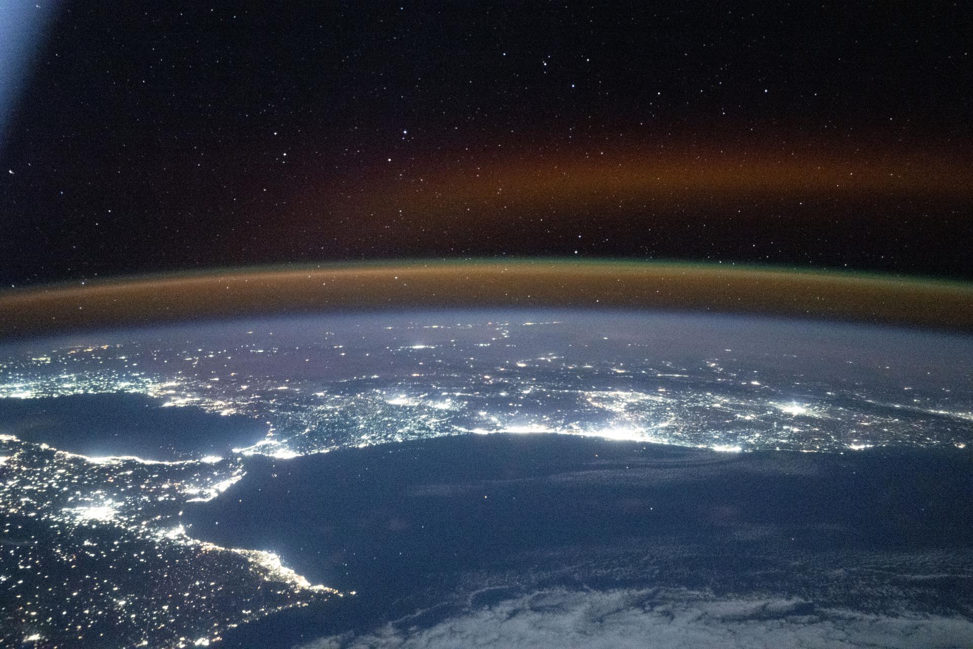 A red-yellow airglow blankets Earth's horizon as the city lights of southwestern Europe and North Africa sparkle in contrast to the Atlantic Ocean and the Mediterranean Sea that separates the two continents. The International Space Station was orbiting 262 miles above the Atlantic at approximately 7:47 p.m. local time when this photograph was taken.
