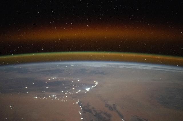 NASA image: A yellow-red airglow blankets Earth's horizon above the Saharan landscape of Algeria