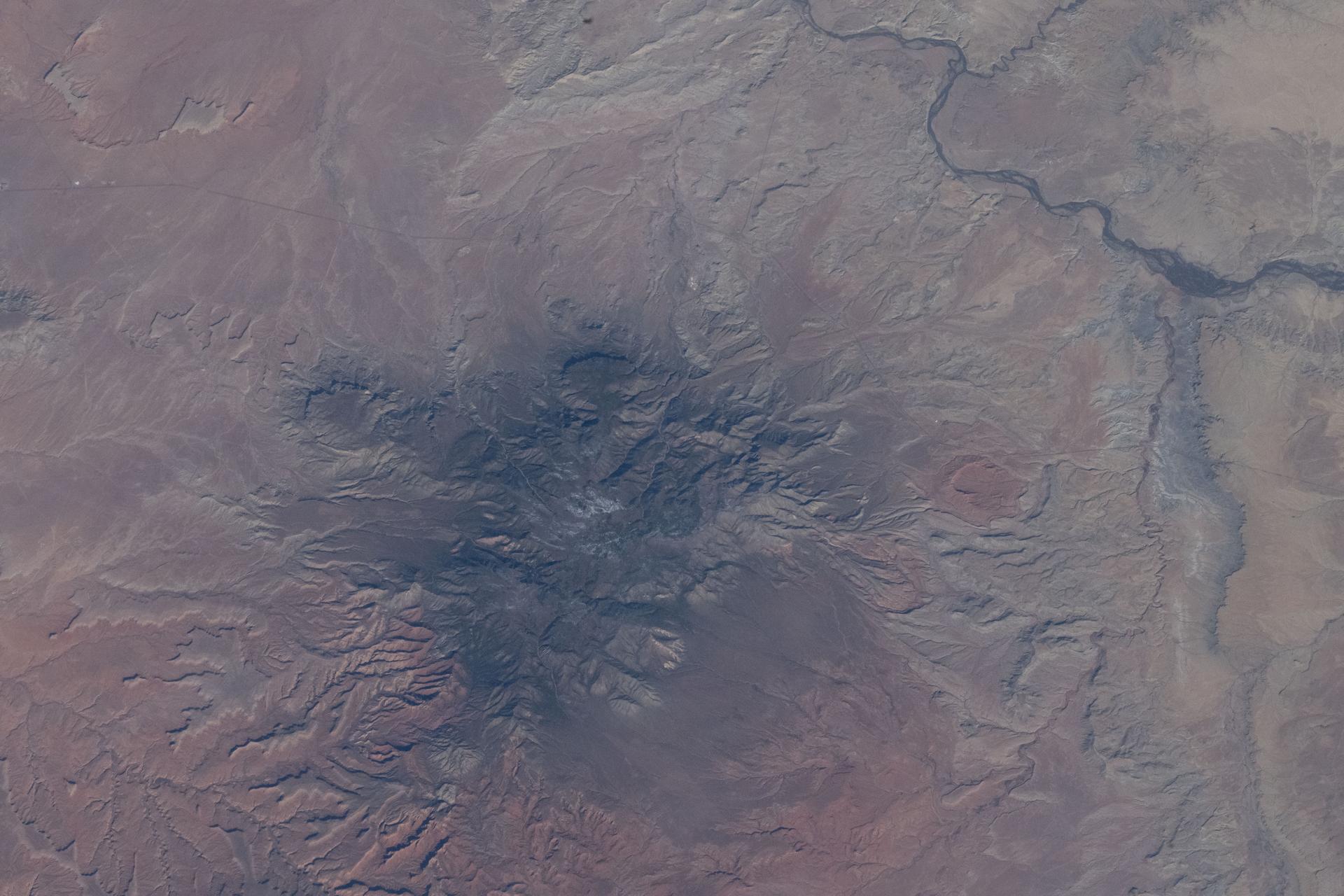 Pastora Peak, rising to 9,413 feet (2,869 meters) inside Arizona's Navajo Nation near the New Mexico border, is seen from the International Space Station as it orbited 263 miles (423 kilometers) above the Grand Canyon State. At upper right, the San Juan River—a major tributary of the Colorado River—winds through New Mexico.