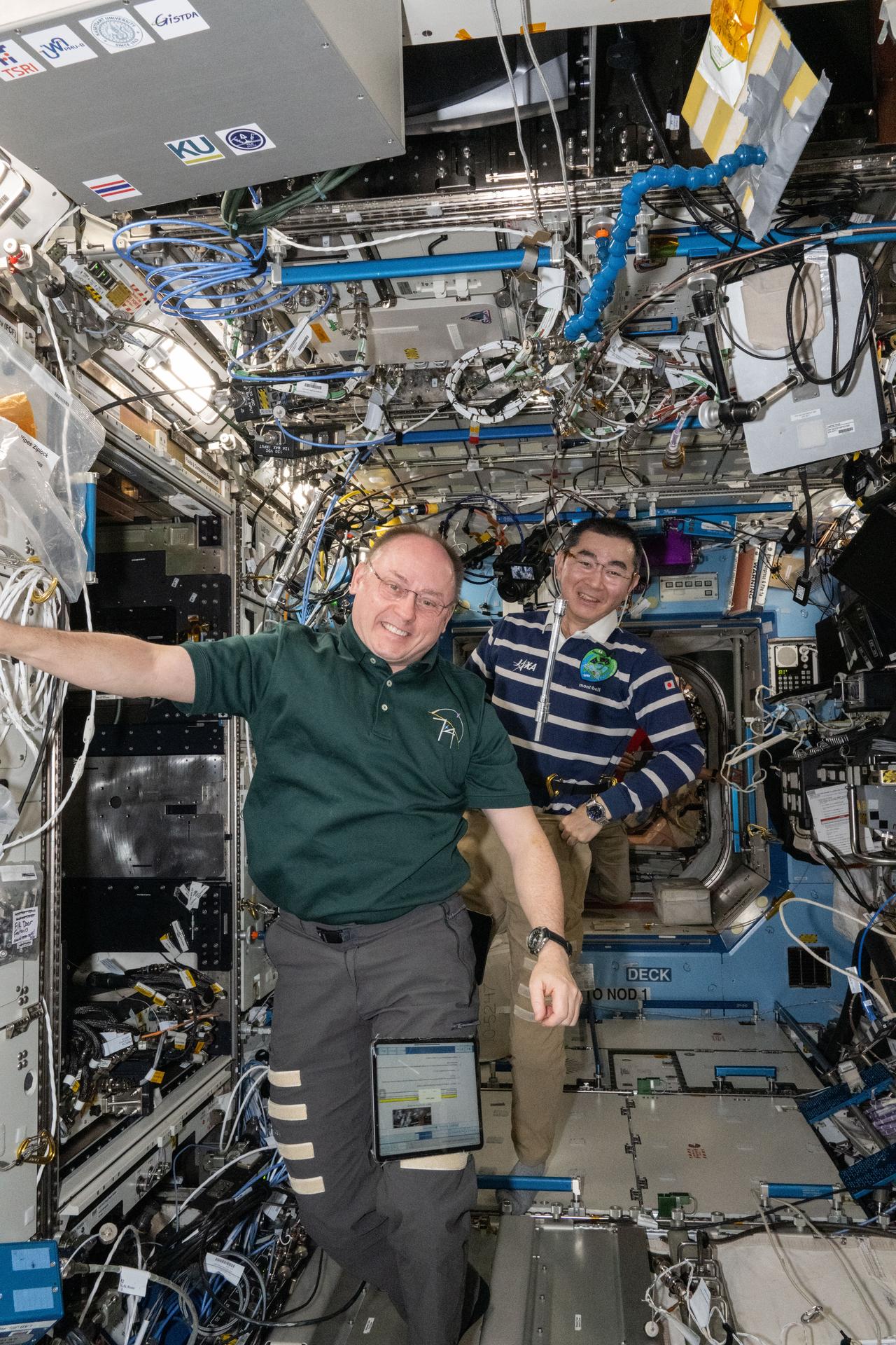 Astronauts Mike Fincke of NASA and Kimiya Yui of JAXA (Japan Aerospace Exploration Agency)—Expedition 74 Commander and Flight Engineer, respectively—smile for a portrait during maintenance activities inside the International Space Station's Destiny laboratory module.