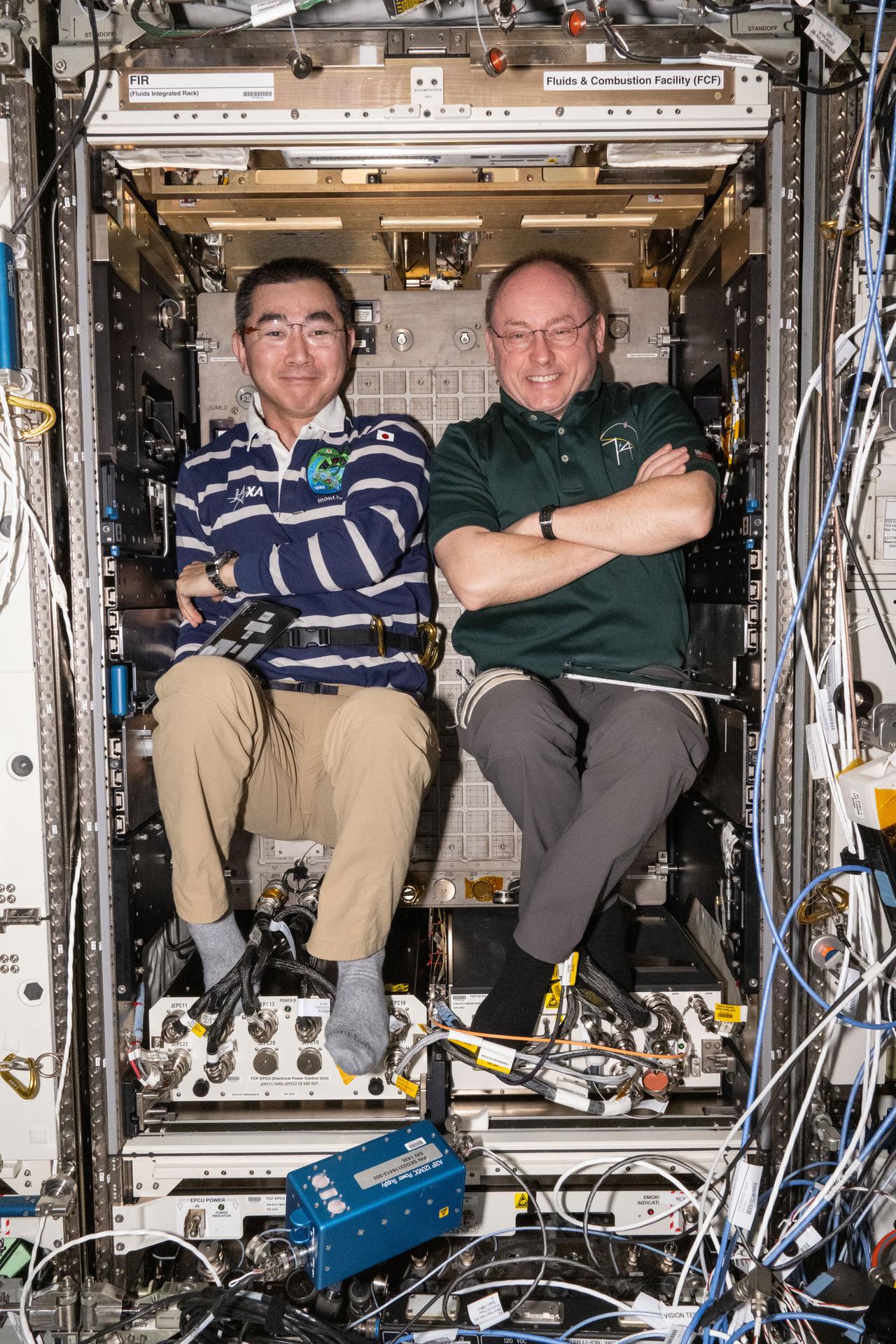 Astronauts Kimiya Yui of JAXA (Japan Aerospace Exploration Agency) and Mike Fincke of NASA—Expedition 74 Flight Engineer and Commander, respectively—pose for a fun portrait during maintenance activities inside the International Space Station’s Destiny laboratory module.