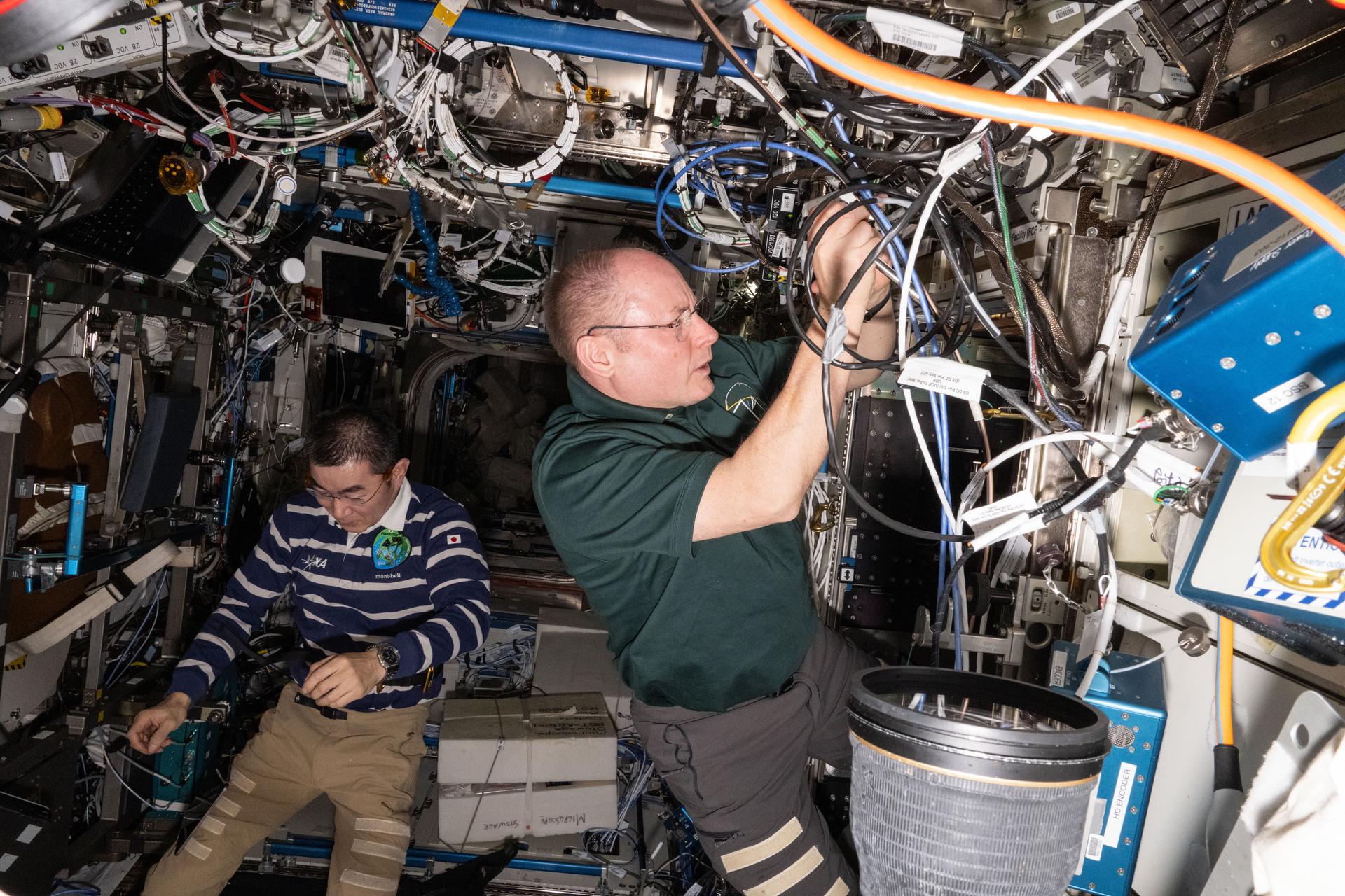 Astronauts Kimiya Yui of JAXA (Japan Aerospace Exploration Agency) and Mike Fincke of NASA—Expedition 74 Flight Engineer and Commander, respectively—work on maintenance activities inside the International Space Station’s Destiny laboratory module.