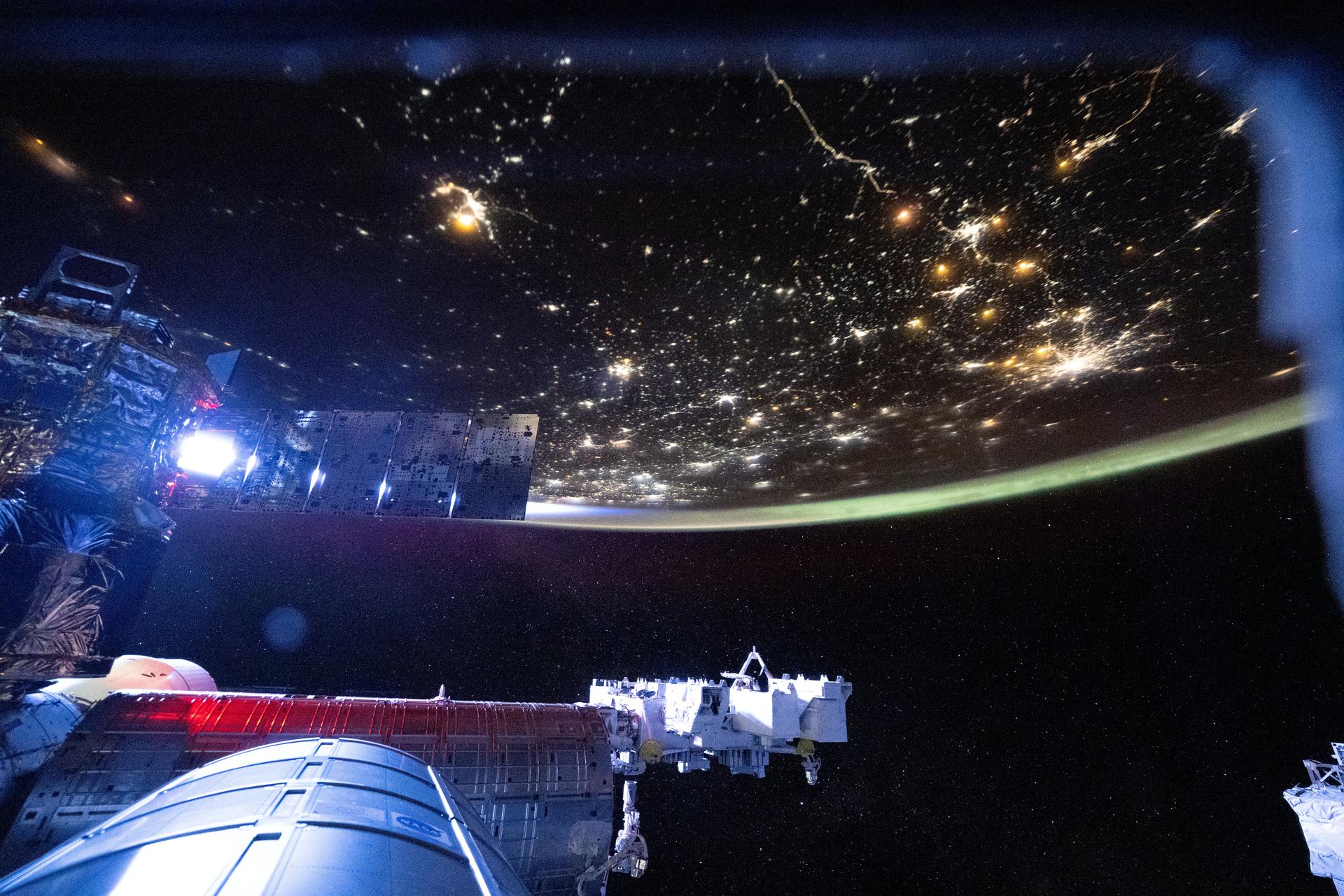 The International Space Station begins to shine brightly as it orbits into a sunrise 264 miles above Volgograd, Russia. A wispy aurora intersects with the atmospheric glow in this photograph taken at approximately 5:23 a.m. local time.