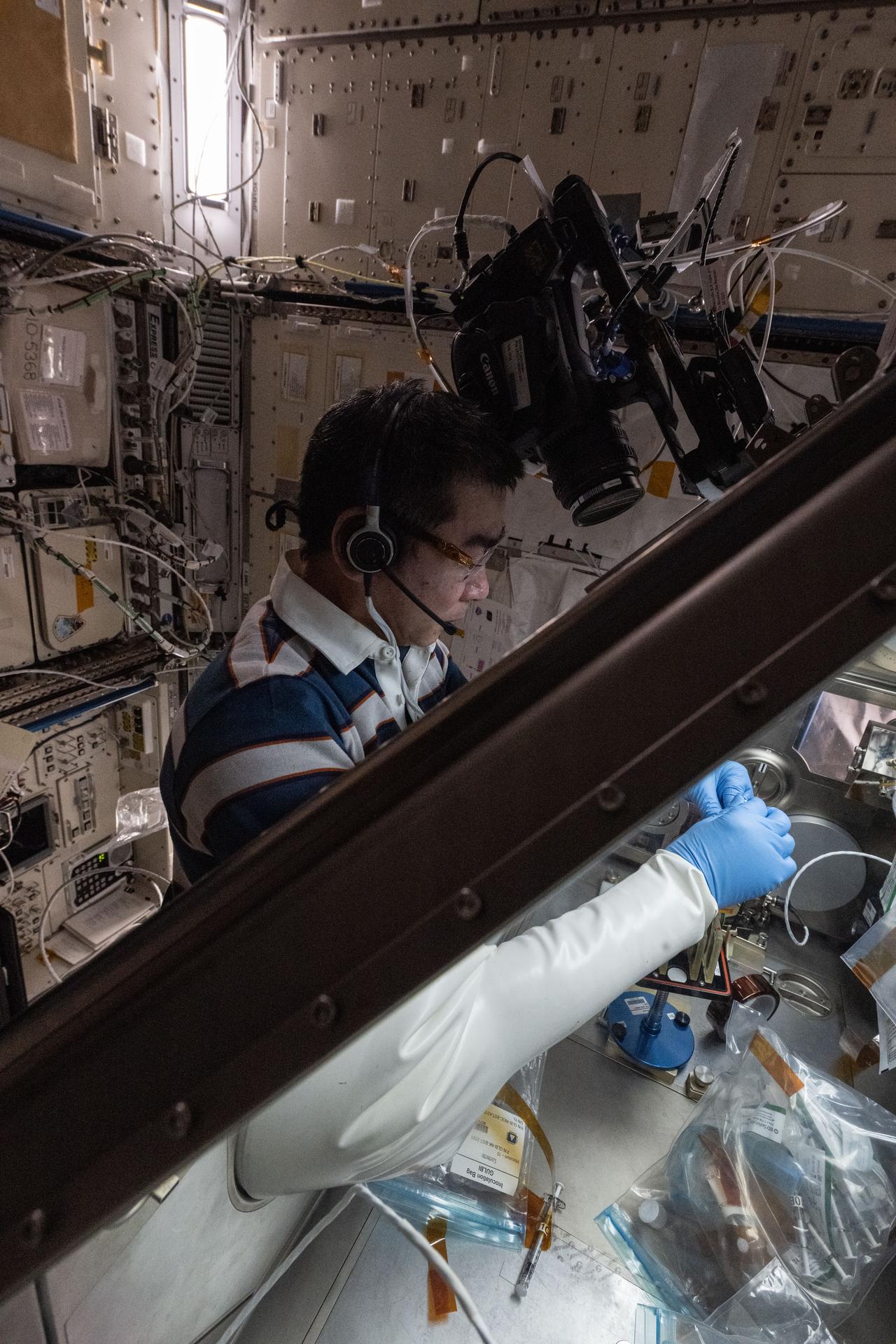 JAXA (Japan Aerospace Exploration Agency) astronaut and Expedition 74 Flight Engineer Kimiya Yui conducts a microbiology research experiment inside the Kibo laboratory module's Life Science Glovebox. Yui was inoculating bacterial samples to study the use of ultraviolet light to disinfect spacecraft surfaces and protect crew health and hardware from biofilms—clusters of microbes that adhere to surfaces and thrive in moist environments.