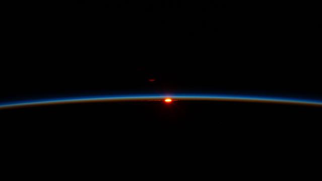 The first rays of an orbital sunrise illuminate Earth’s atmosphere