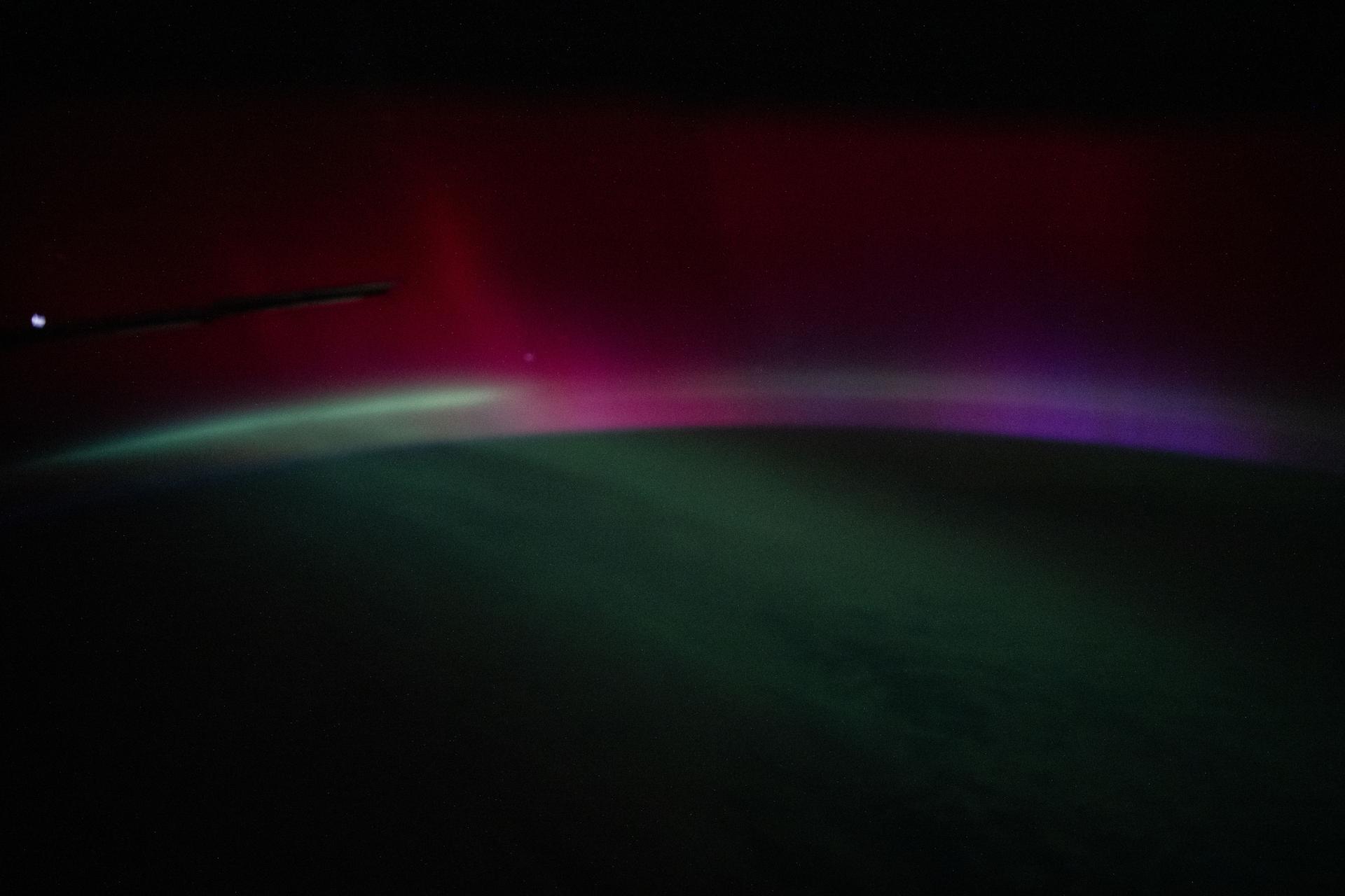 A wispy, multi-colored aurora—created by a geomagnetic storm and producing rare colors such as deep red and purple—is pictured above the Atlantic Ocean. The International Space Station was orbiting 262 miles above Earth off the coast of Portugal at approximately 10:31 p.m. local time when this photograph was taken.