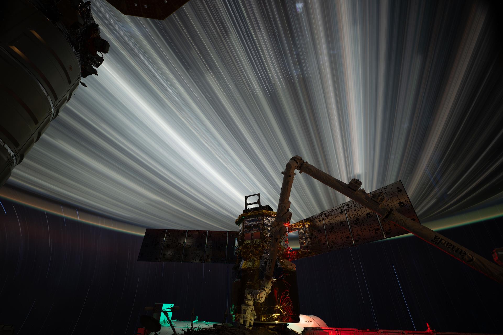 Star trails and city lights streak by in this long-duration photograph taken from the International Space Station as it orbited 261 miles above the India-Pakistan border at approximately 2:35 a.m. local time. In the foreground is JAXA’s (Japan Aerospace Exploration Agency) HTV-X1 cargo craft, berthed to the Harmony module’s Earth-facing port, with the Canadarm2 robotic arm perched on a portable data grapple fixture in front.