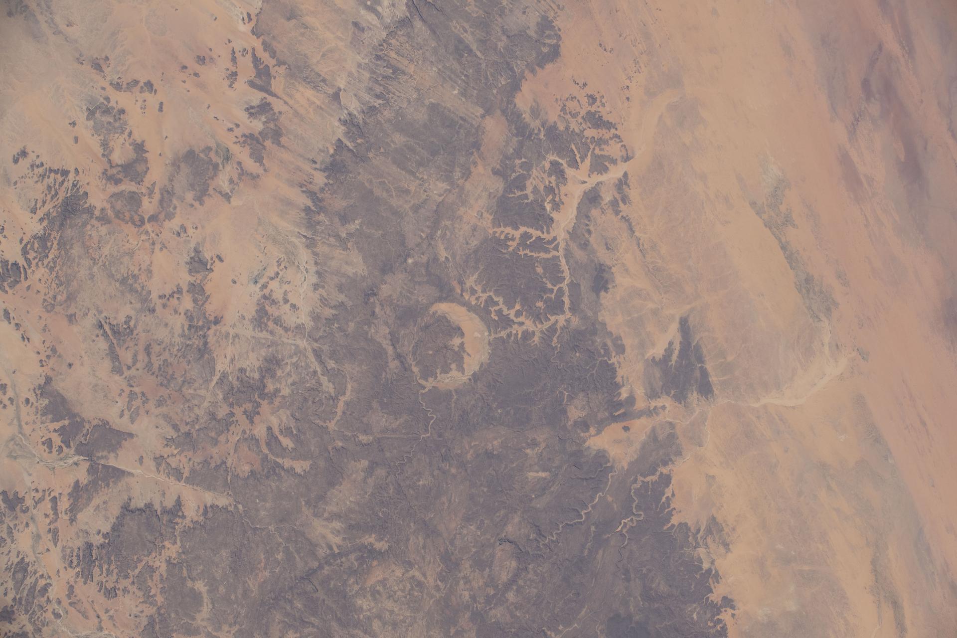 Crater Gweni-Fada (center) is an eroded meteorite impact structure located on Chad's Ennedi Plateau, a UNESCO World Heritage Site, and is estimated to be less than 345 million years old. The International Space Station was orbiting 260 miles above the African nation when this photograph was taken.